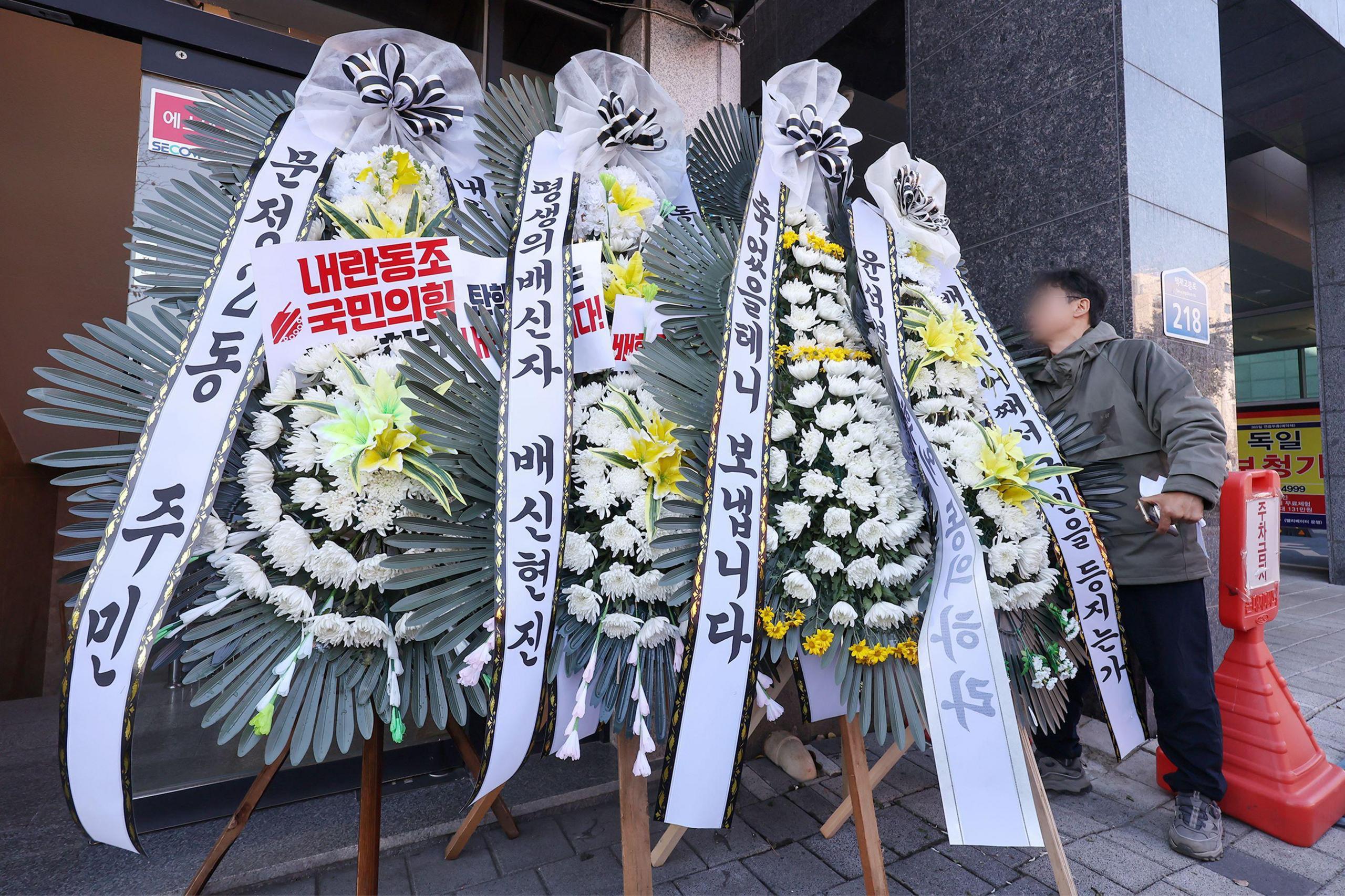 Funeral flowers - large floral displays with banners - are seen outside a building