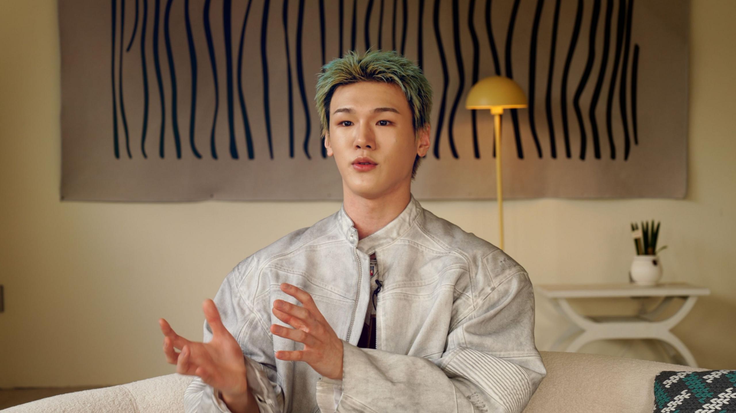 Bain, in a white jacket, during an interview with BBC Korean