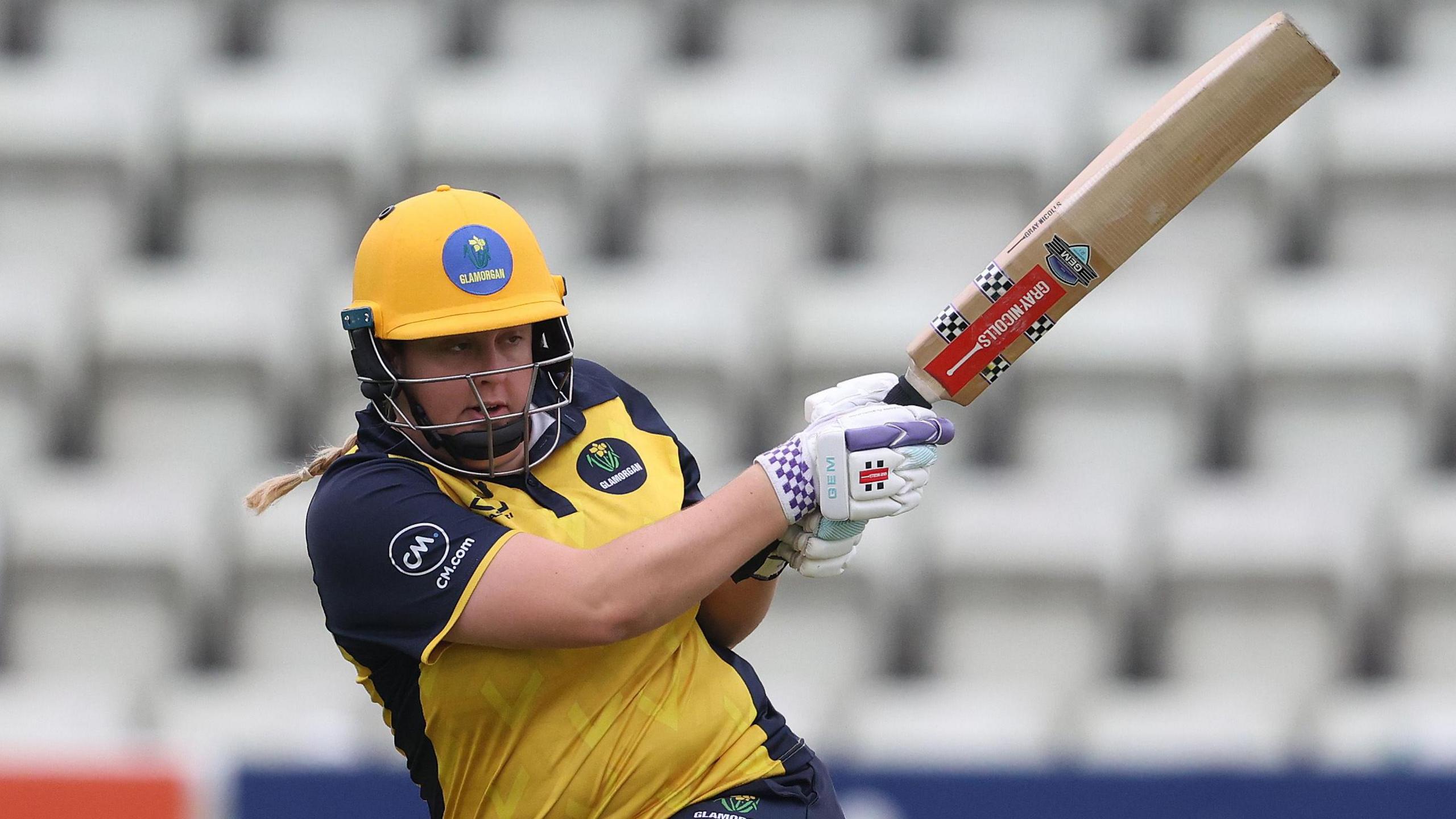 Abbey Freeborn plays a hook shot for Glamorgan in yellow kit