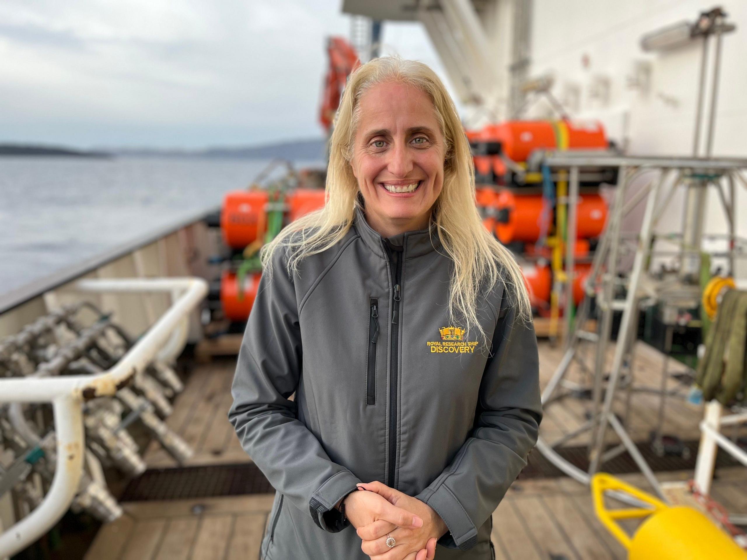 A photograph of Professor Evi Nomikou on deck of the RRS Discovery with red and yellow equipment around her 