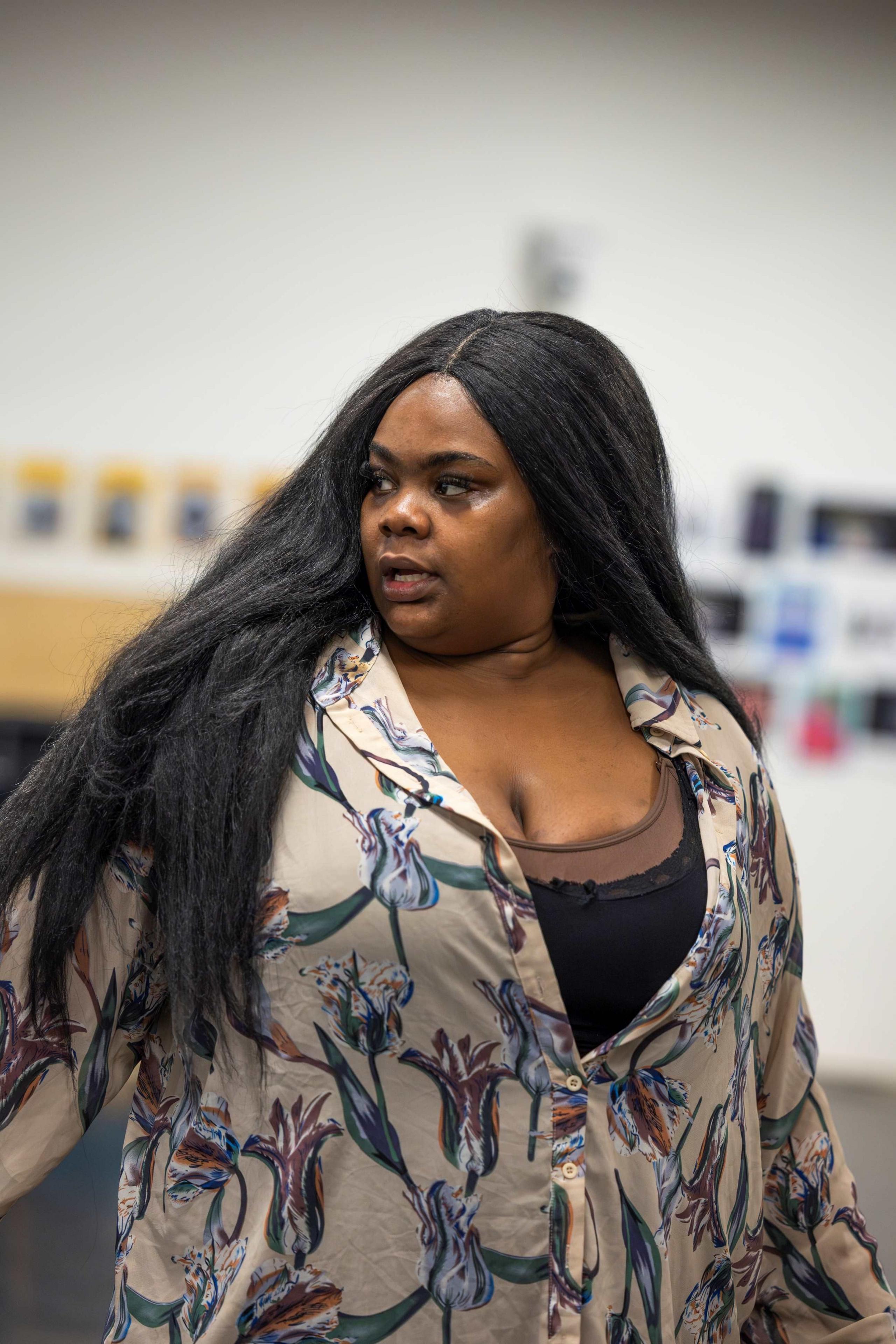 Analisa Lamola in rehearsal wearing a black vest and cream shirt with flowers with her long black hair down