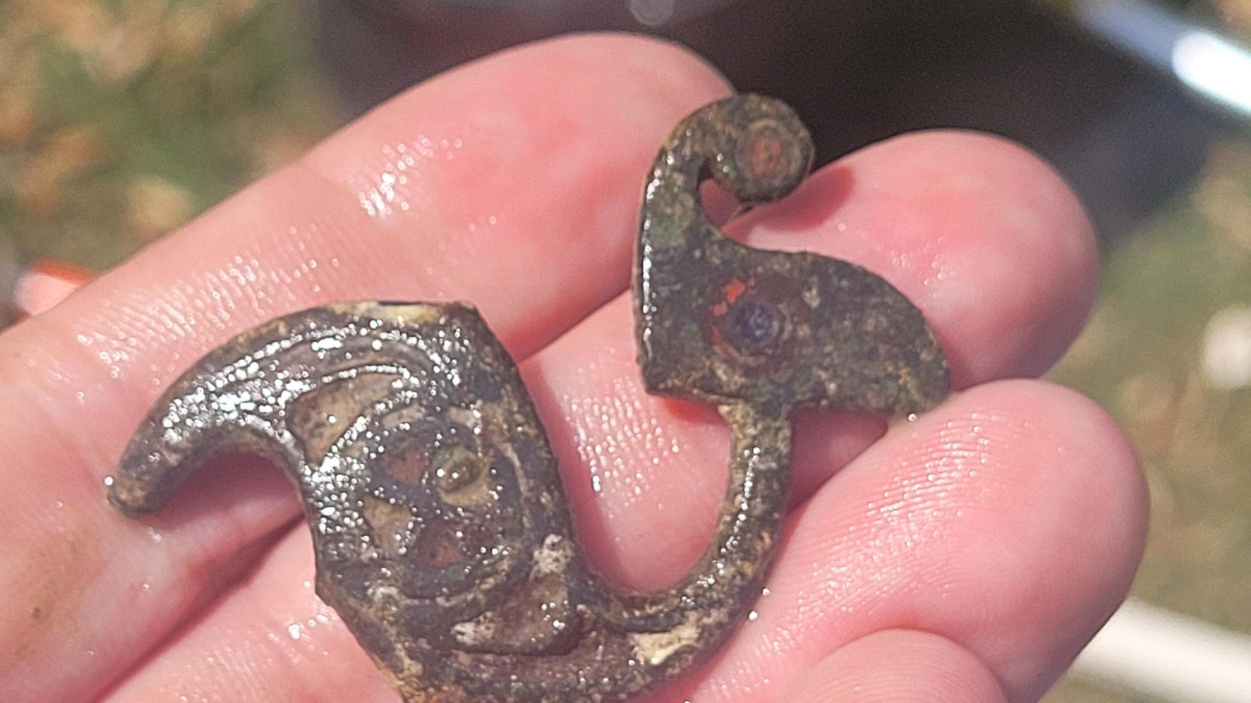 A bronze hair pin found during the dig is held by an archaeologist.