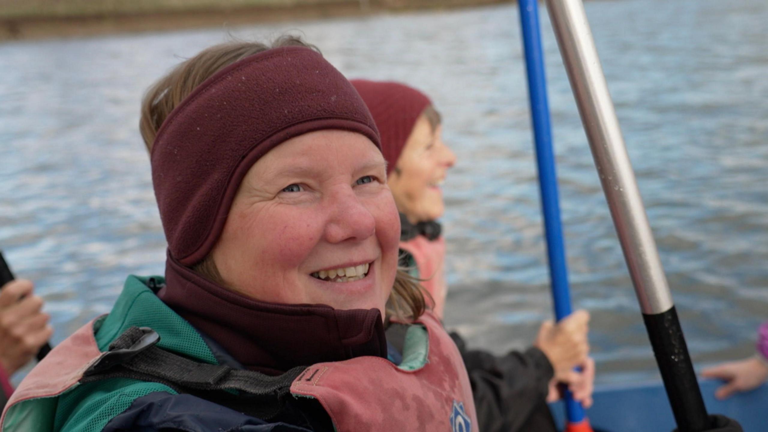 Ann Polak is wearing a deep burgundy head band to keep her ears warm as she tried dragon boat paddling for the very first time. Her big smile and rosy cheeks match her enthusiasm for the experience despite and said she was grateful for "a very kind crew" after struggling with coordination.