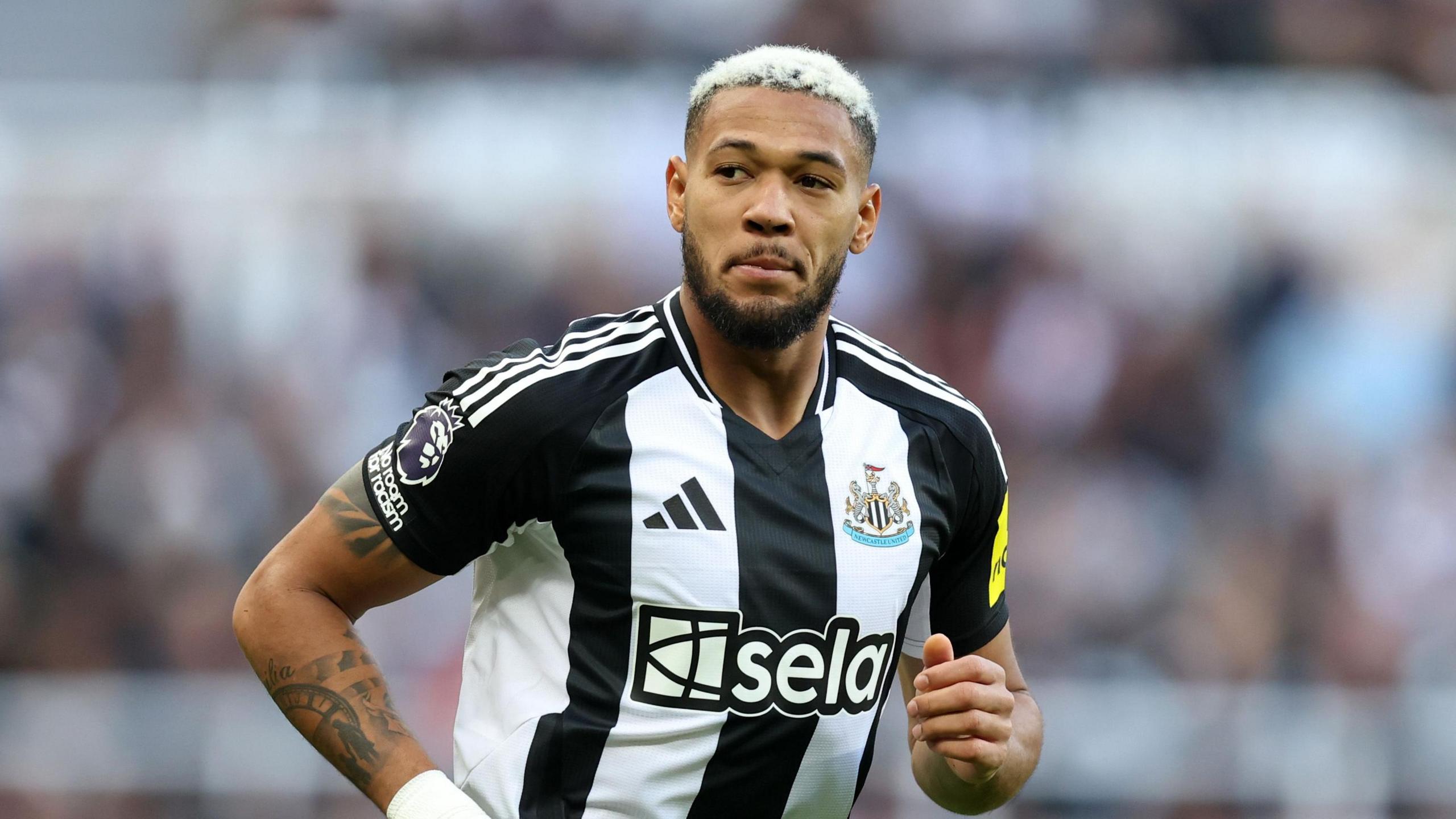 Joelinton running wearing a black and white Newcastle United strip.