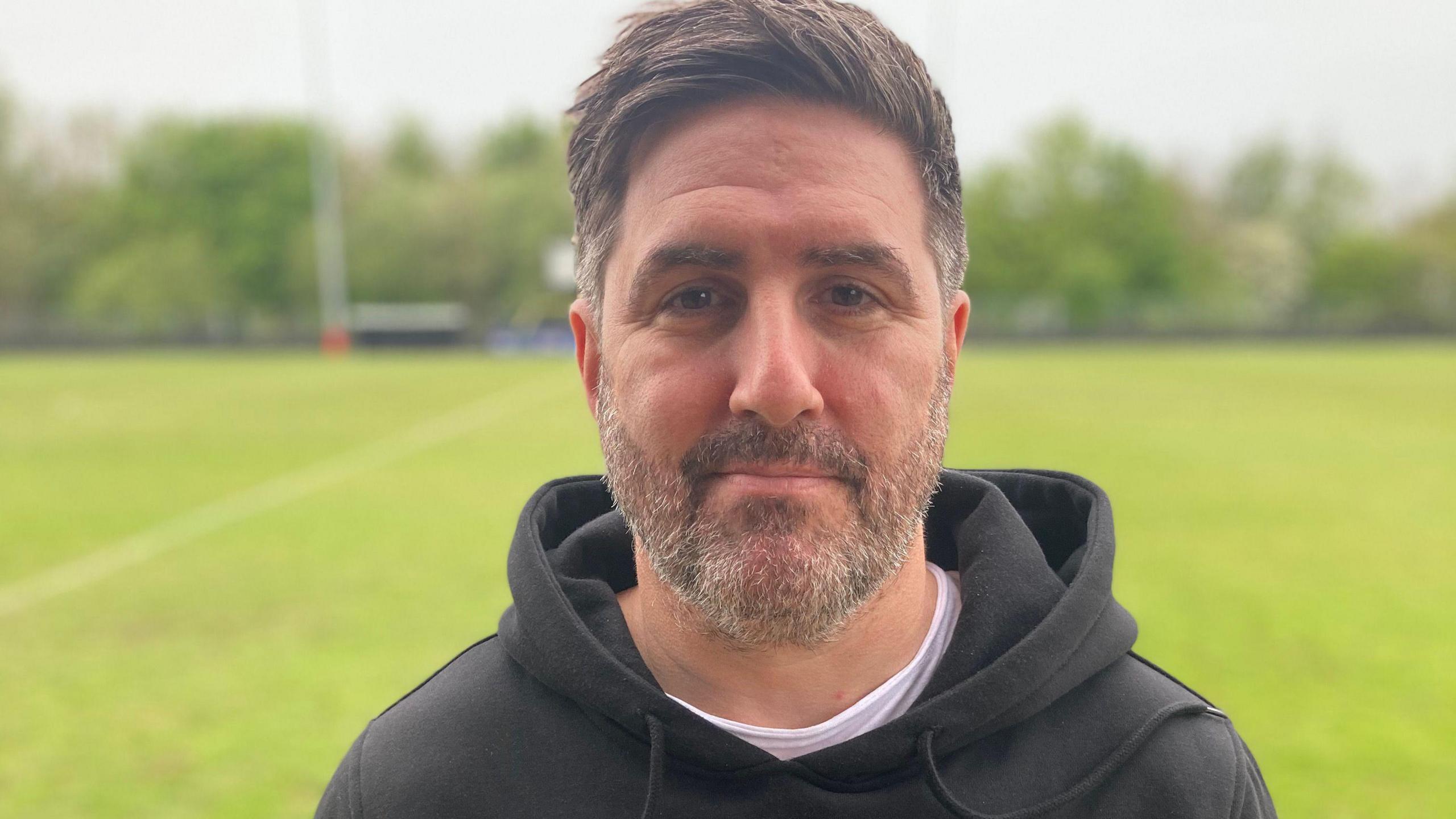 Peter McCormack smiles with a football pitch in the background
