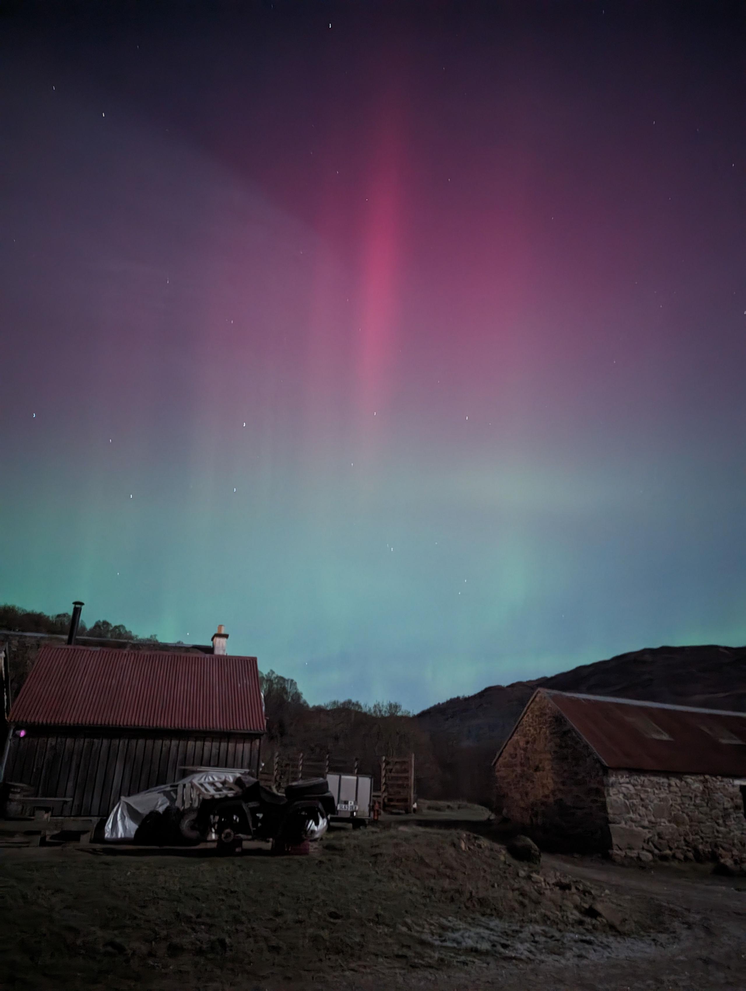 An aurora above some farm buildings