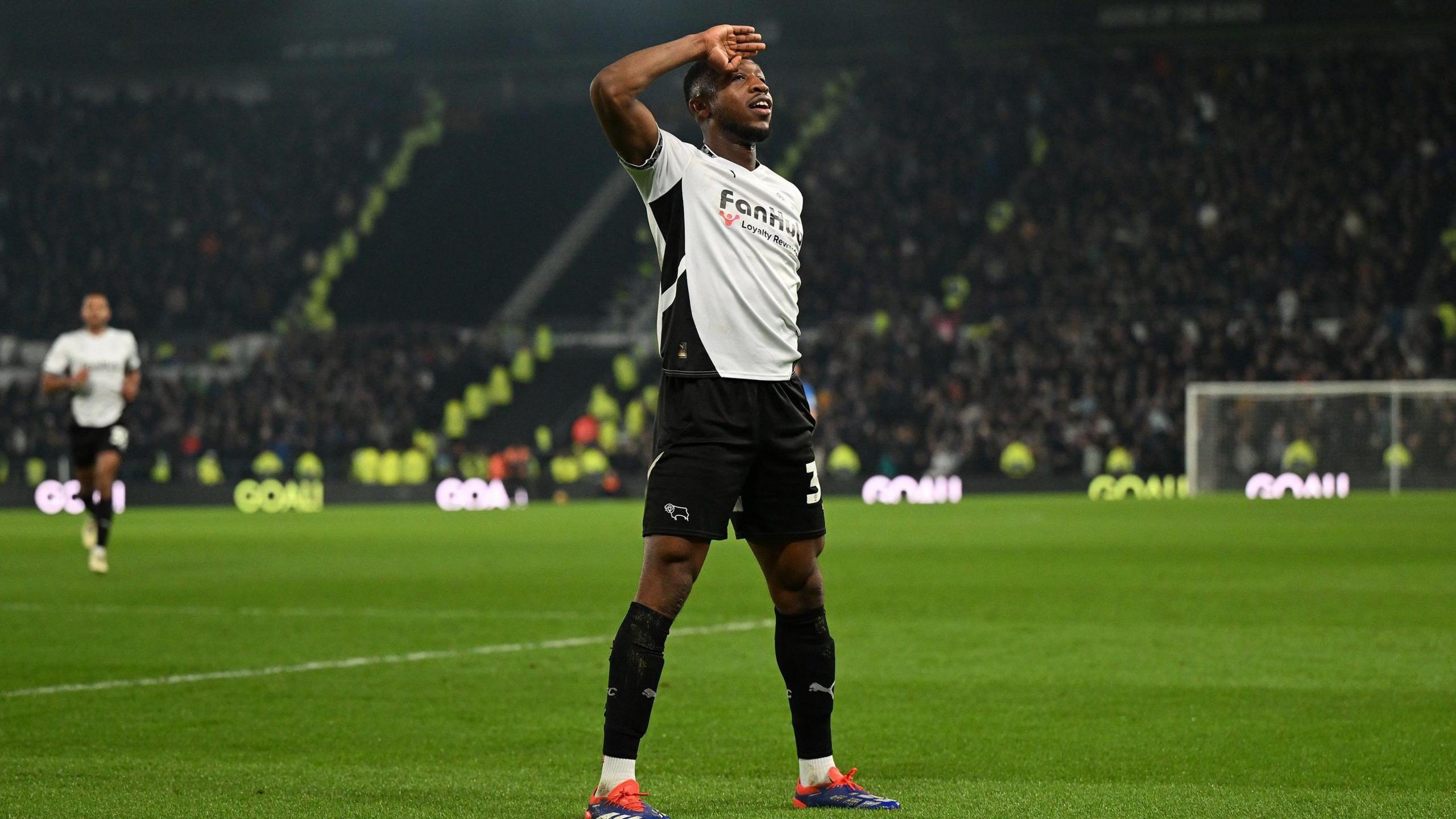 A photo of Ebou Adams saluting the crowd in his home Derby kit on the pitch in December 2024