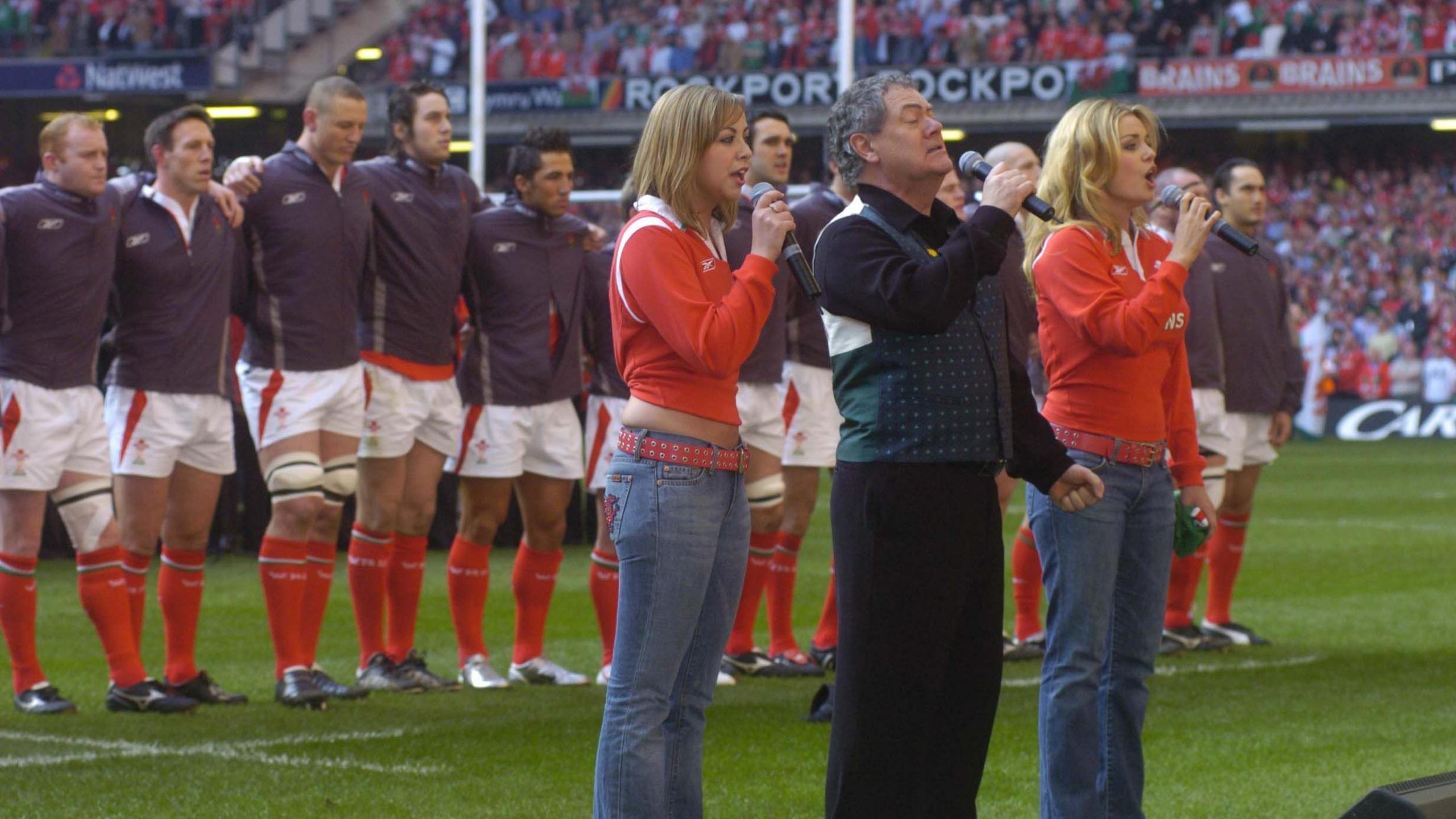 Charlotte Church, Max Boyce and Katherine Jenkins sing with the Wales team arm in arm behind.