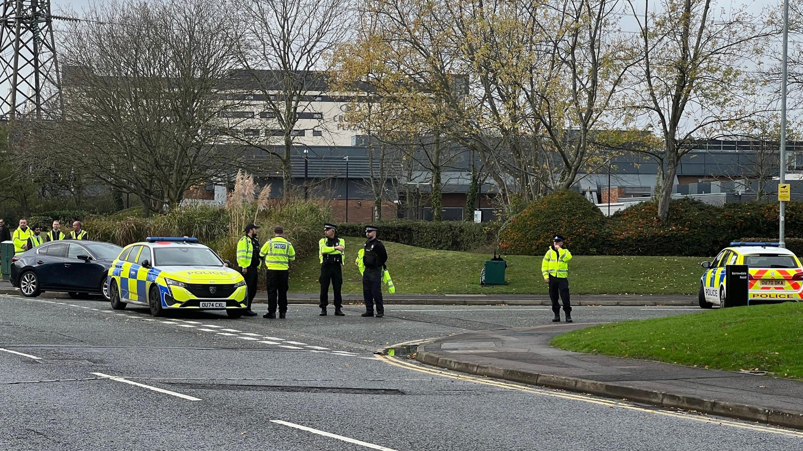 Two market police cars and several police parked at the corner of a road.