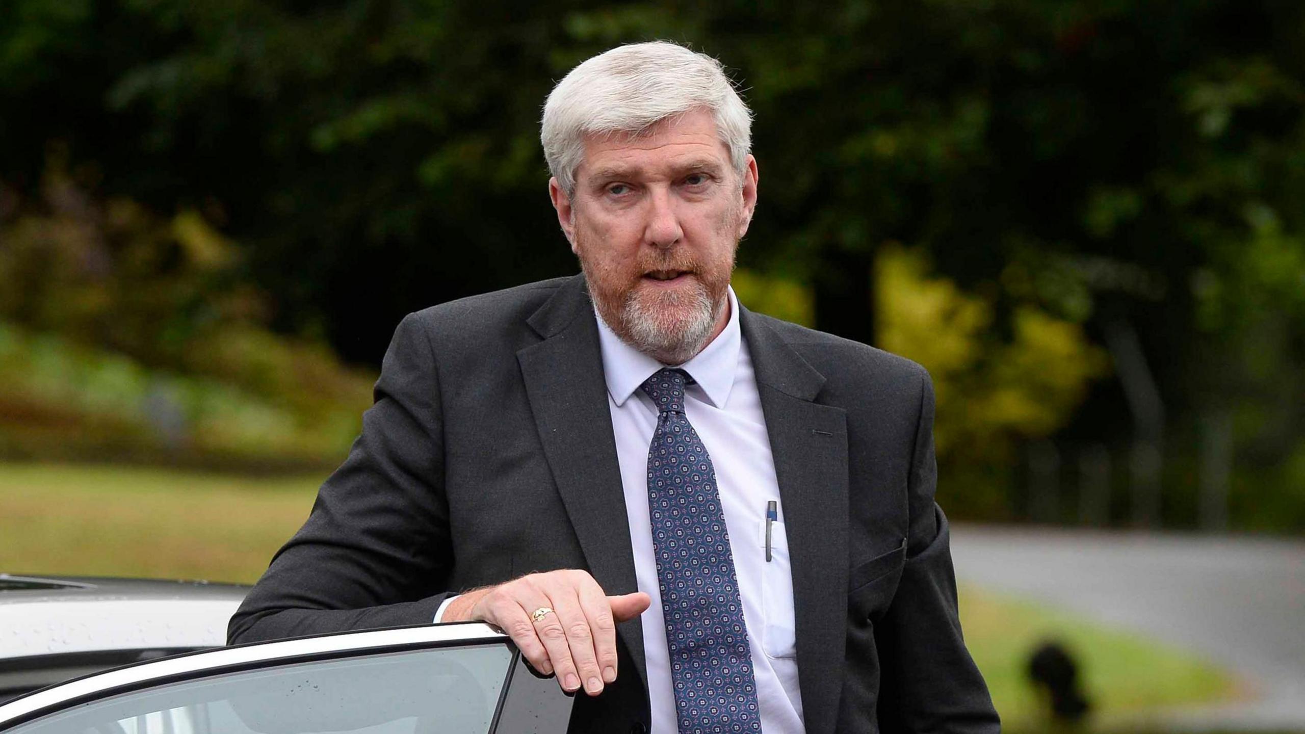 John O'Dowd, a man with grey hair and a ginger-grey beard and wearing a dark suit and blue tie