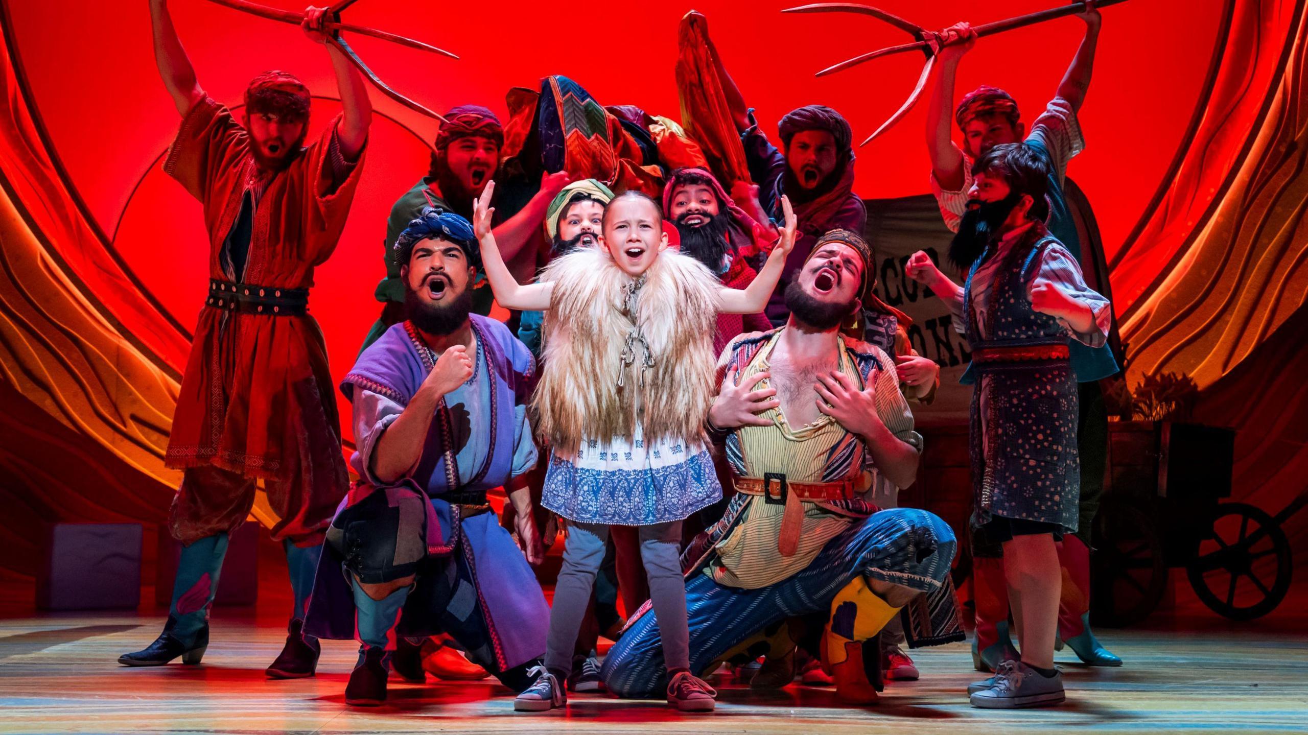 Some of the cast members of Joseph and the Amazing Technicolour Dreamcoat perform on stage at the Bristol Hippodrome. They are dressed in ragged clothes and are singing passionately towards the camera