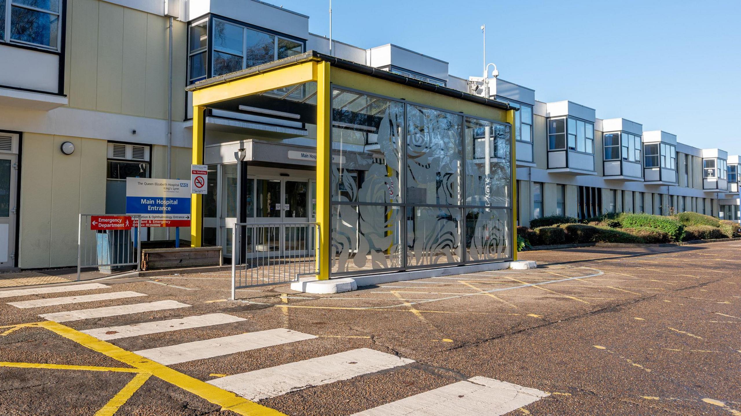 An exterior view of an entrance at the Queen Elizabeth Hospital in King's Lynn. It is two-storey building. There is a covered area outside where emergency vehicles can transfer patients. 