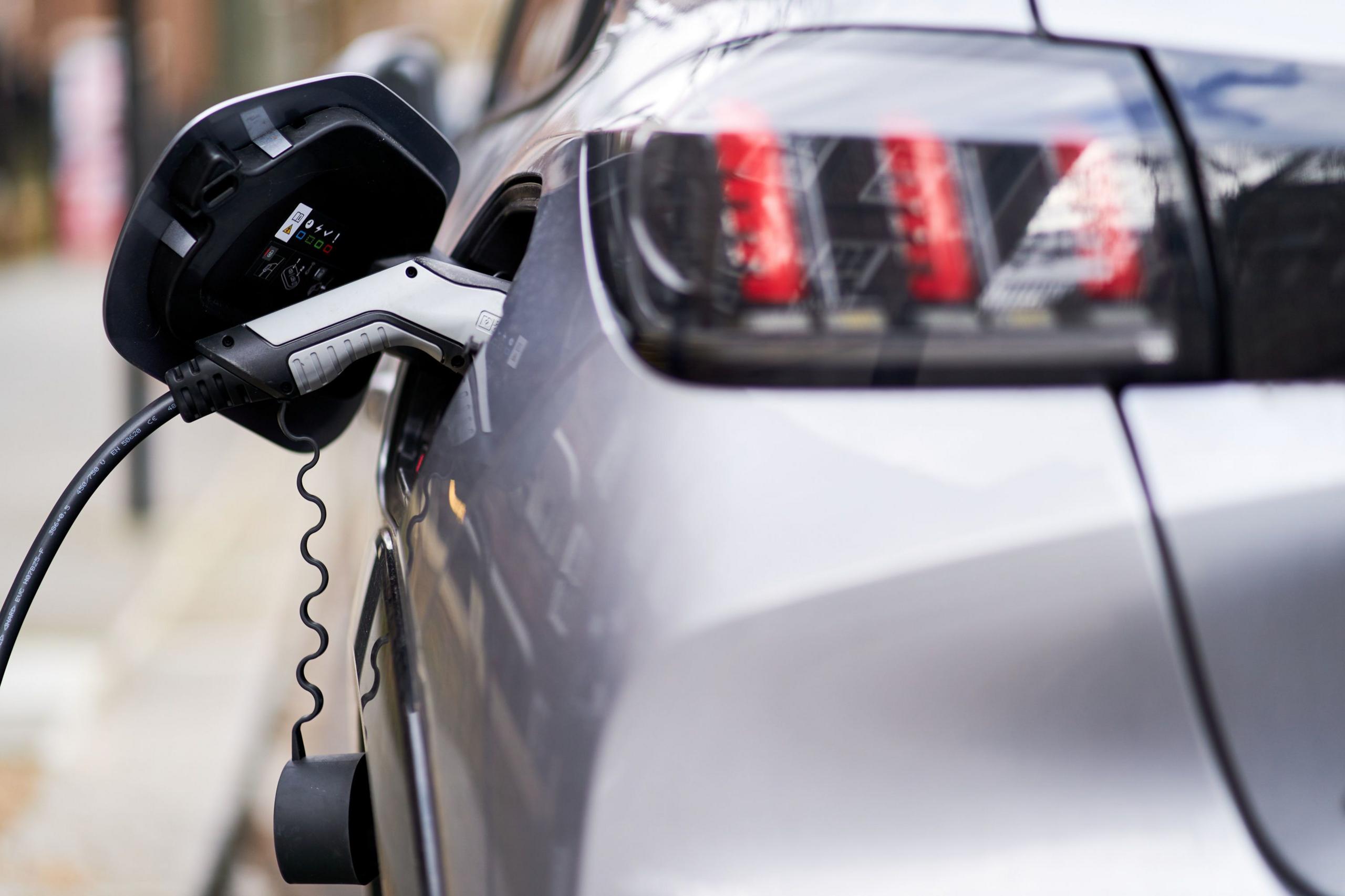 An electric silver car being charged