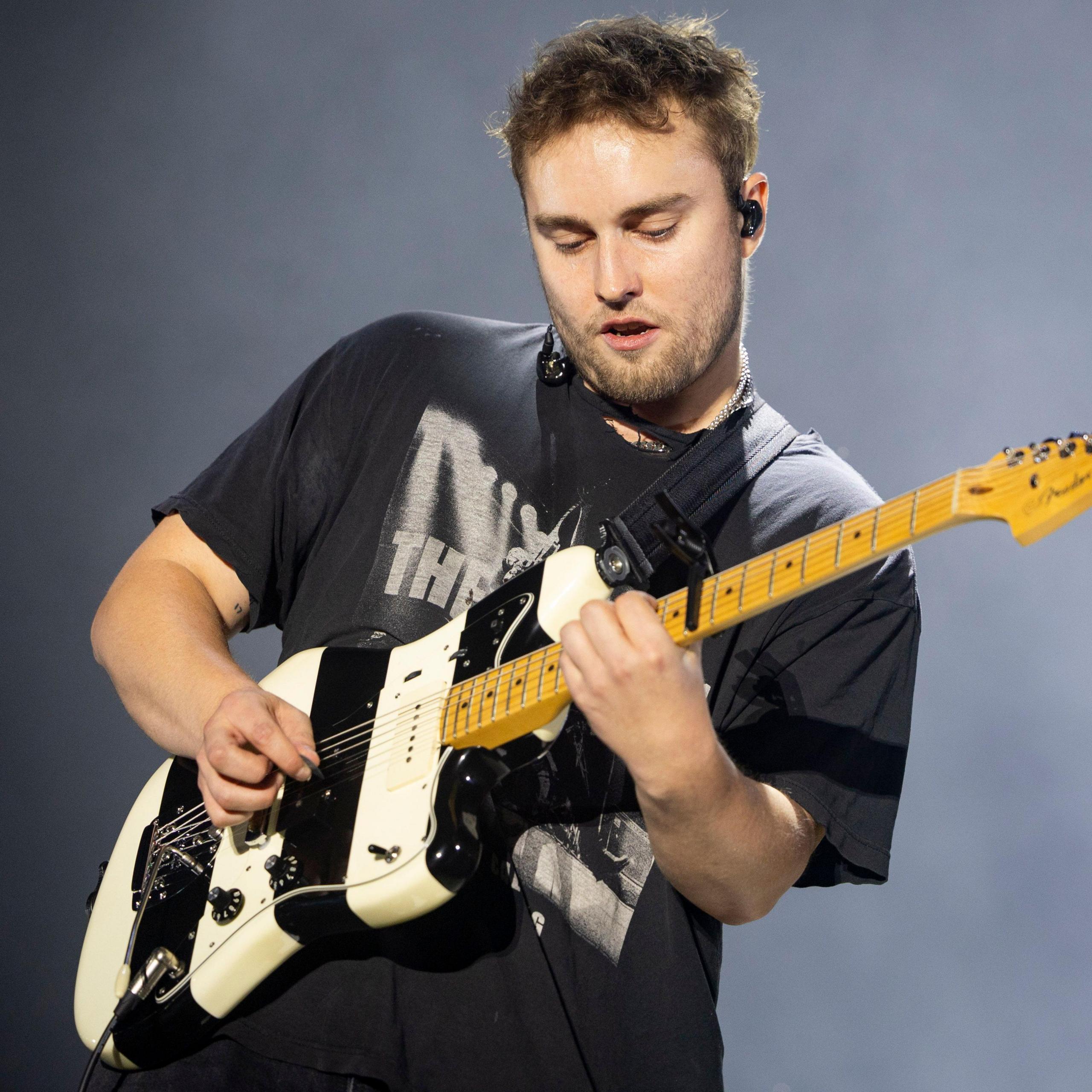 Sam Fender on stage playing a black and white striped guitar