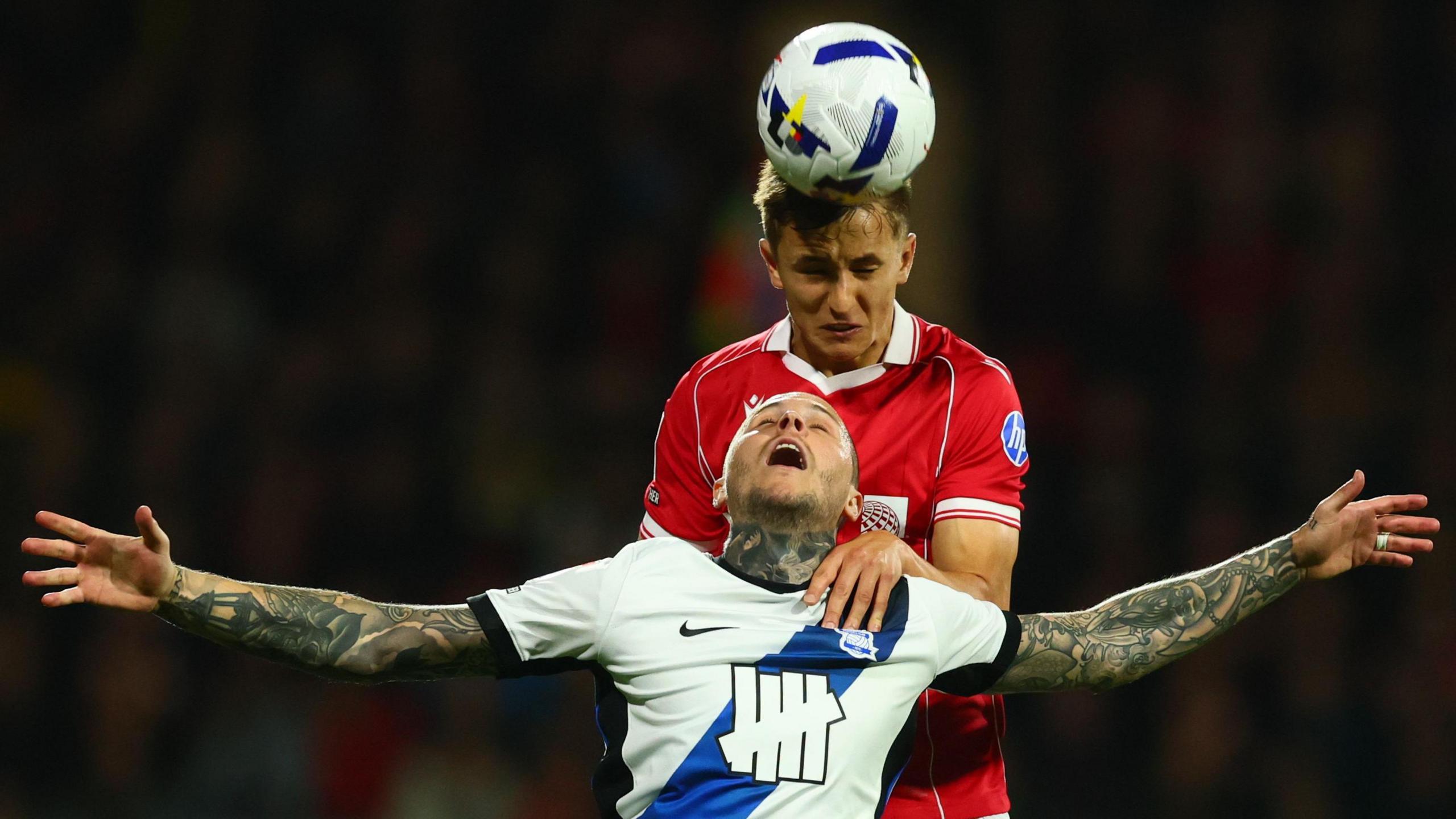 Max Cleworth leaps above Lyndon Dykes to head the ball