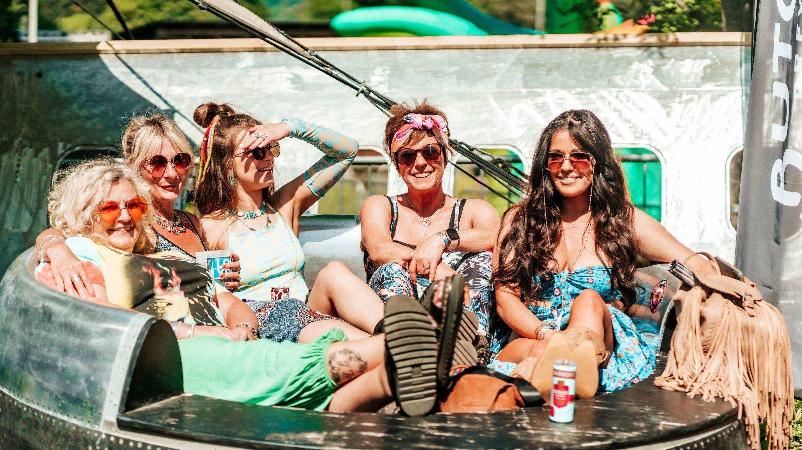 Five women sitting in a big round chair in the sunshine