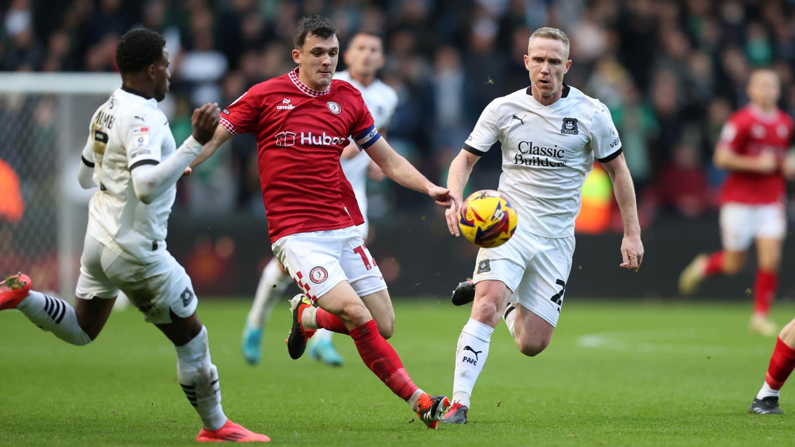 Players from Bristol City and Plymouth Argyle contest the ball at Ashton Gate. City are in their traditional red shirts and white shorts, while Plymouth are in an all-white change kit