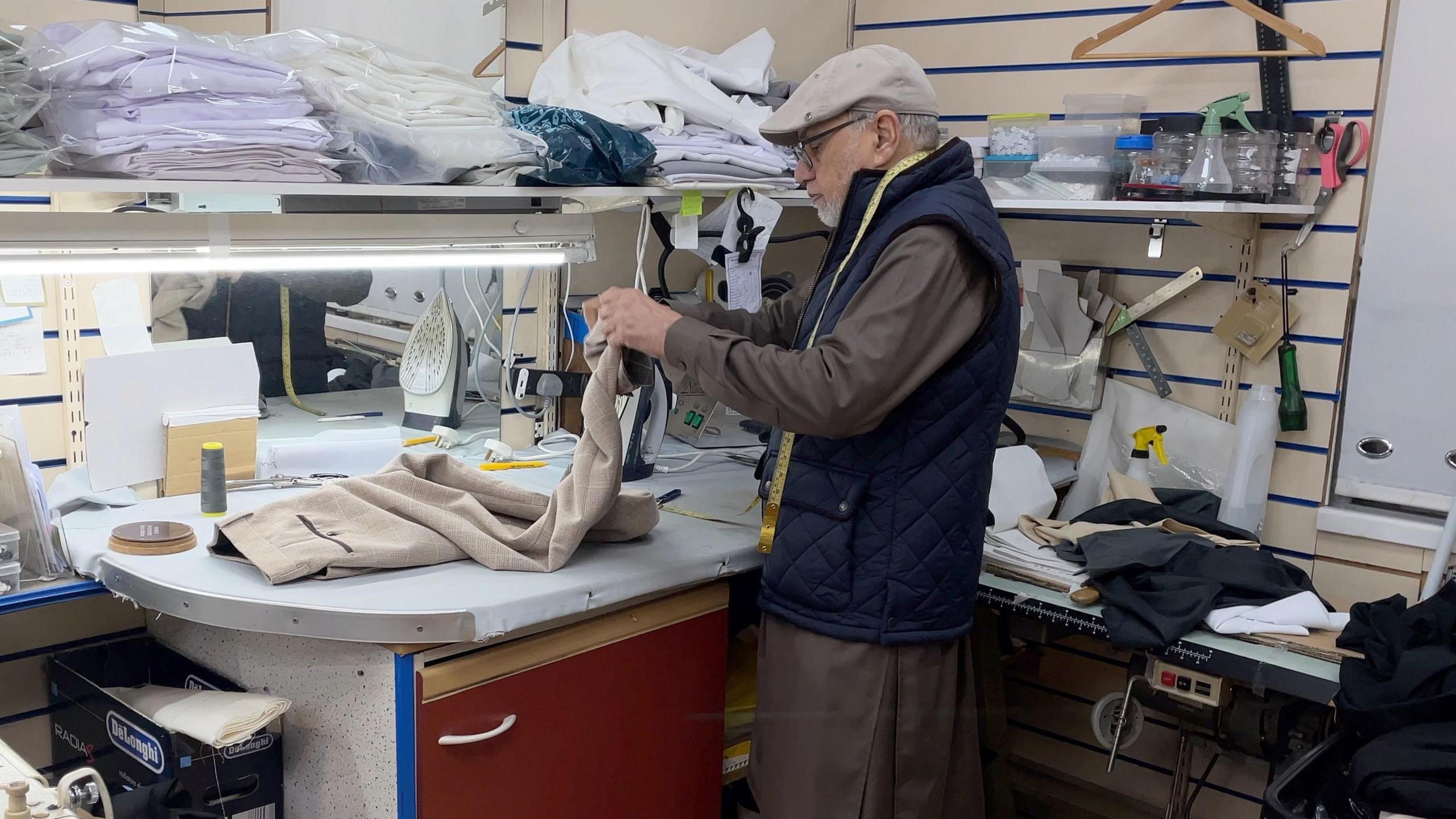 Barket adjusting the hem on a pair of trousers for a customer.