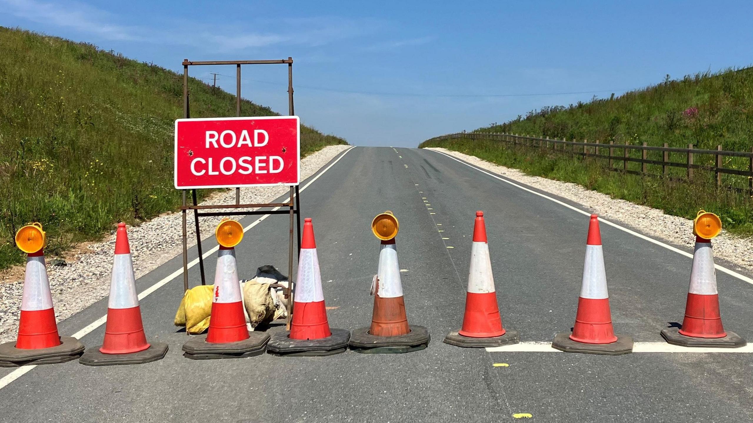 A slipway leading to the A30 is closed off with traffic cones and a red sign with white lettering that reads ROAD CLOSED.