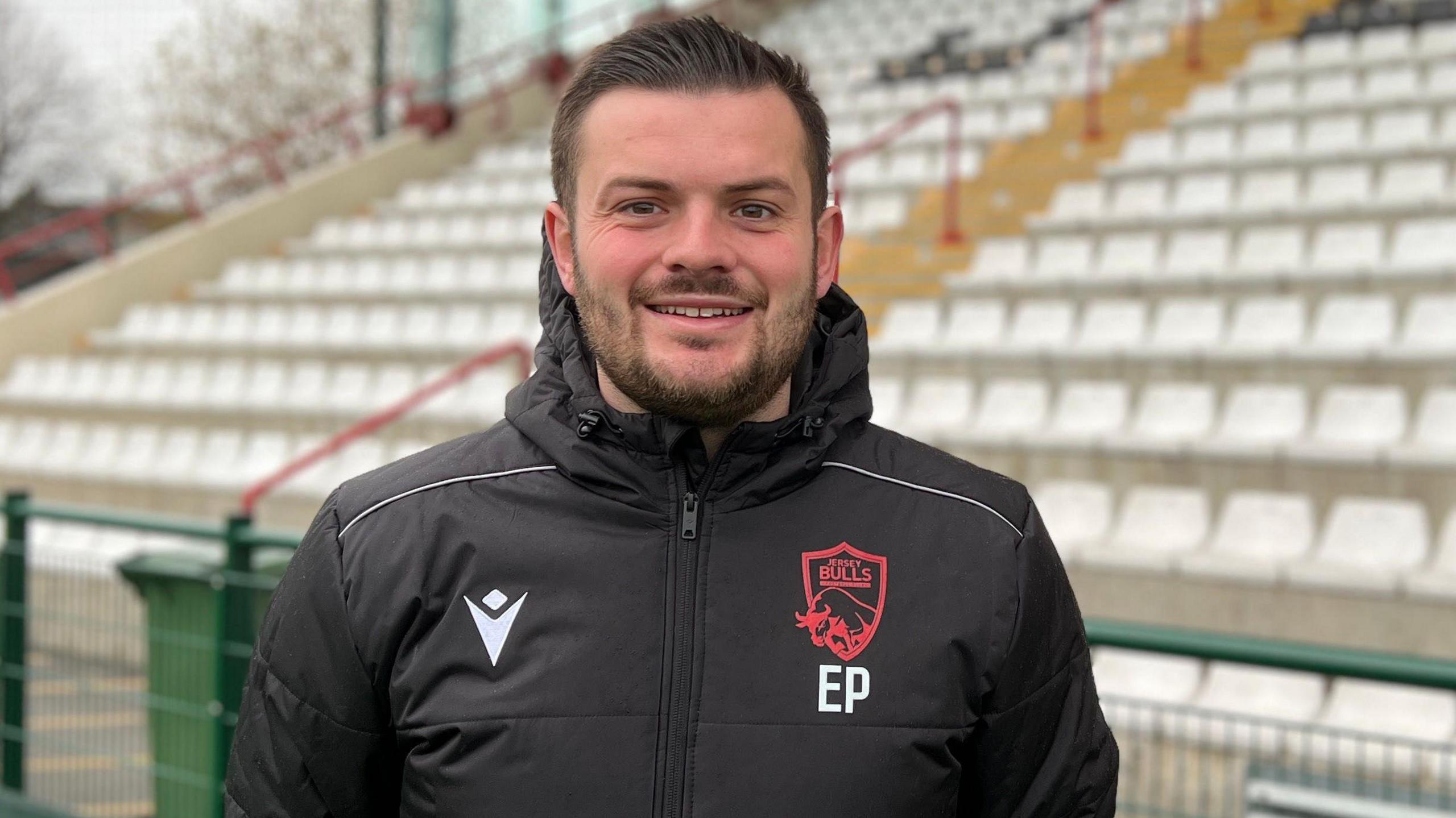Elliot Powell standing inside the ground with his hands by his side looking straight at the camera