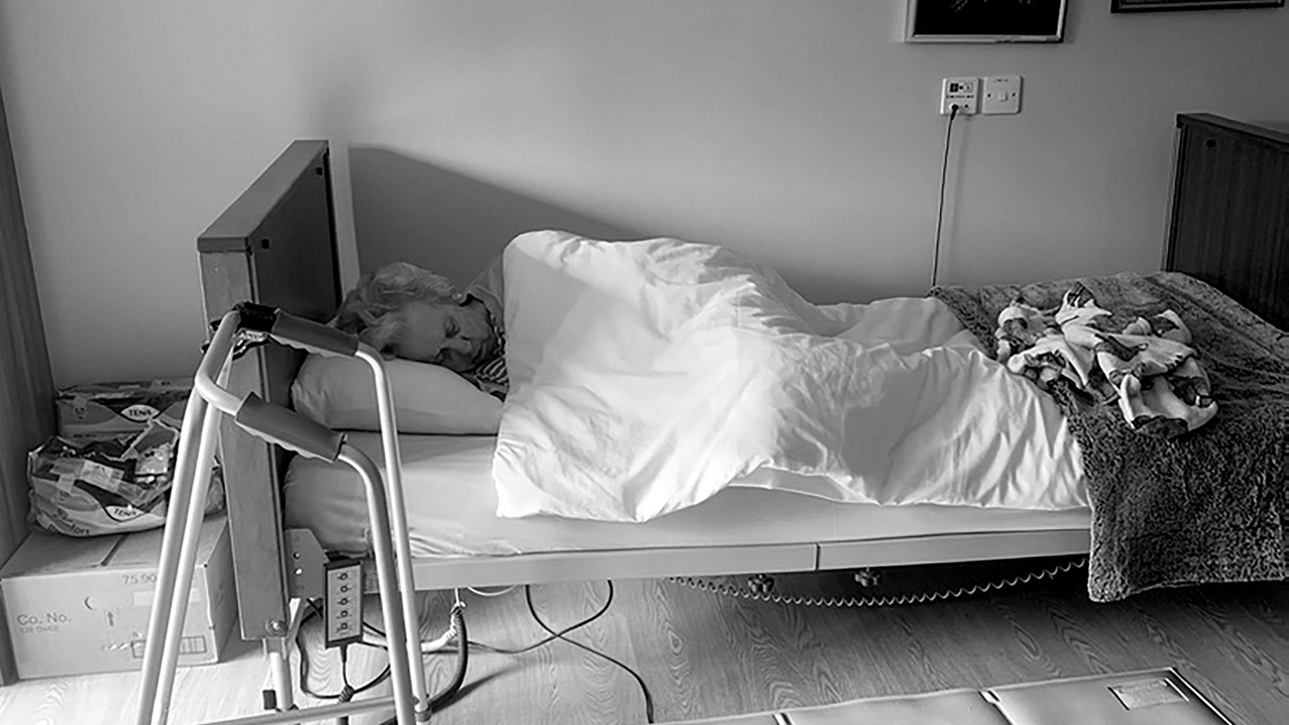 Vivian Harris asleep in her care home bed. The image is black and white.
