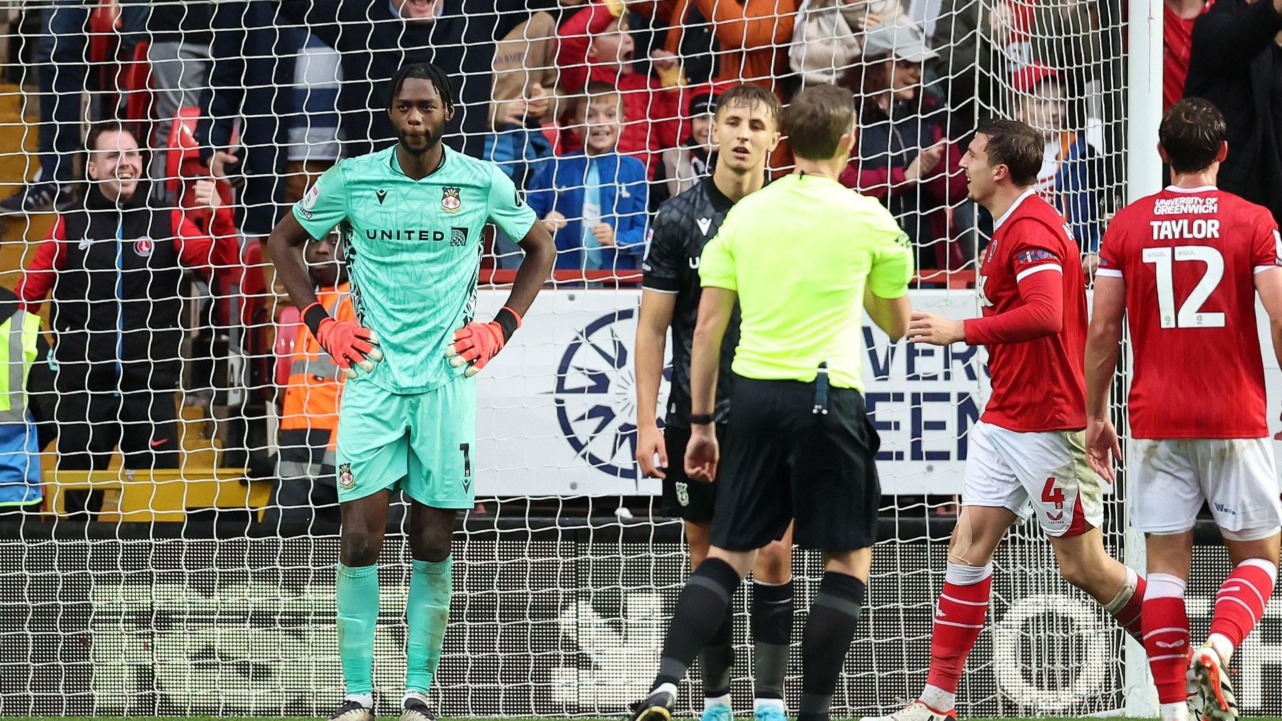 Wrexham goalkeeper Arthur Okonkwo shows dejection after a penalty is awarded to Charlton Athletic

