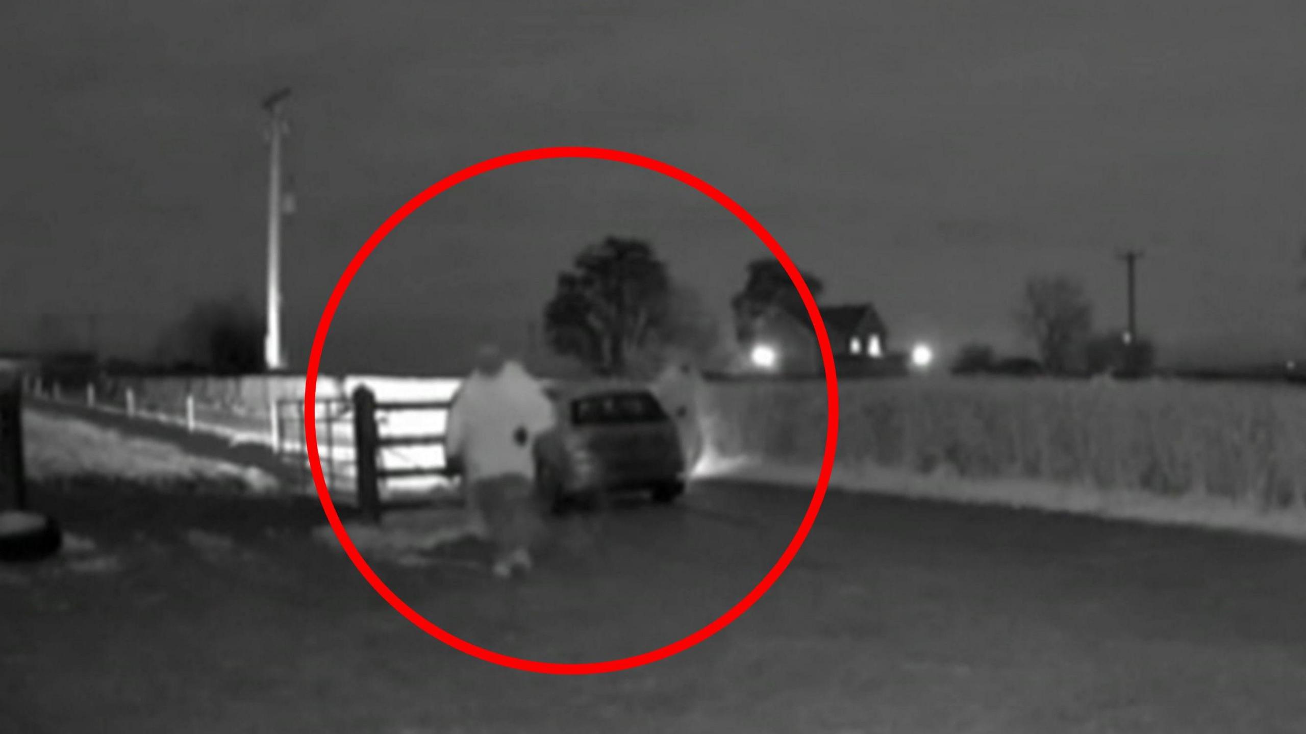 Big red circle highlighting two people trying to run and break into a farm. It's a CCTV image from a doorbell type camera.