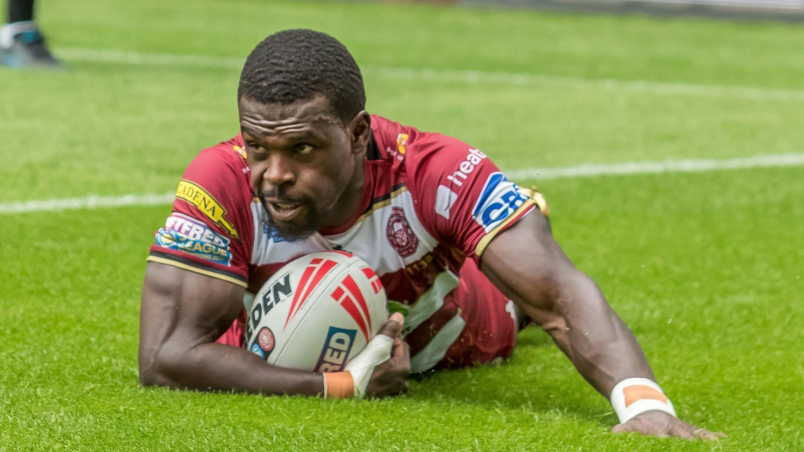 Christian Wade, with the ball in his right hand, having dived over the line to score a try for Wigan Warriors