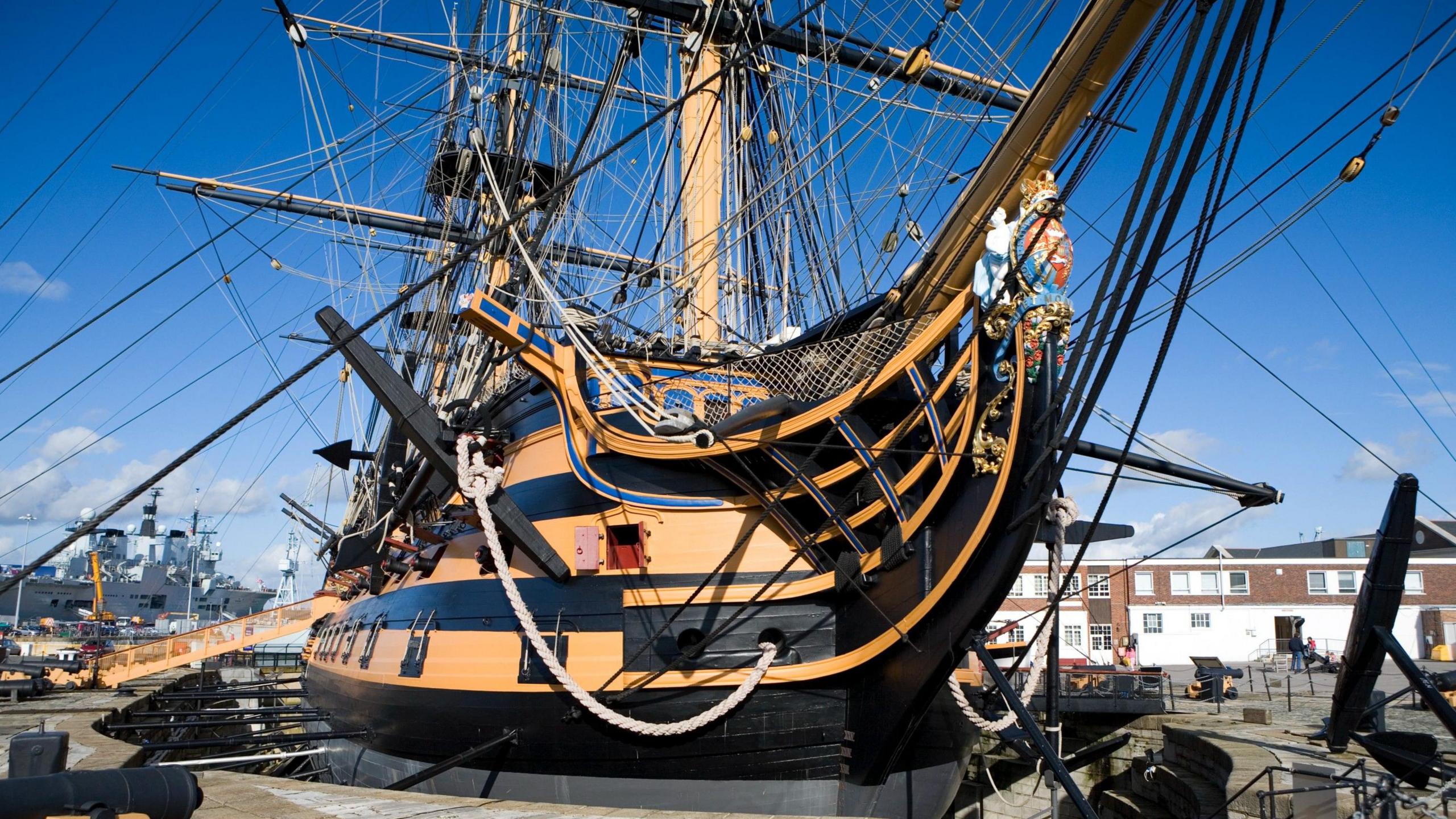 Nelson's Flagship HMS Victory in dry dock at Portsmouth harbour UK, new modern warship HMS Ark Royal in background.
