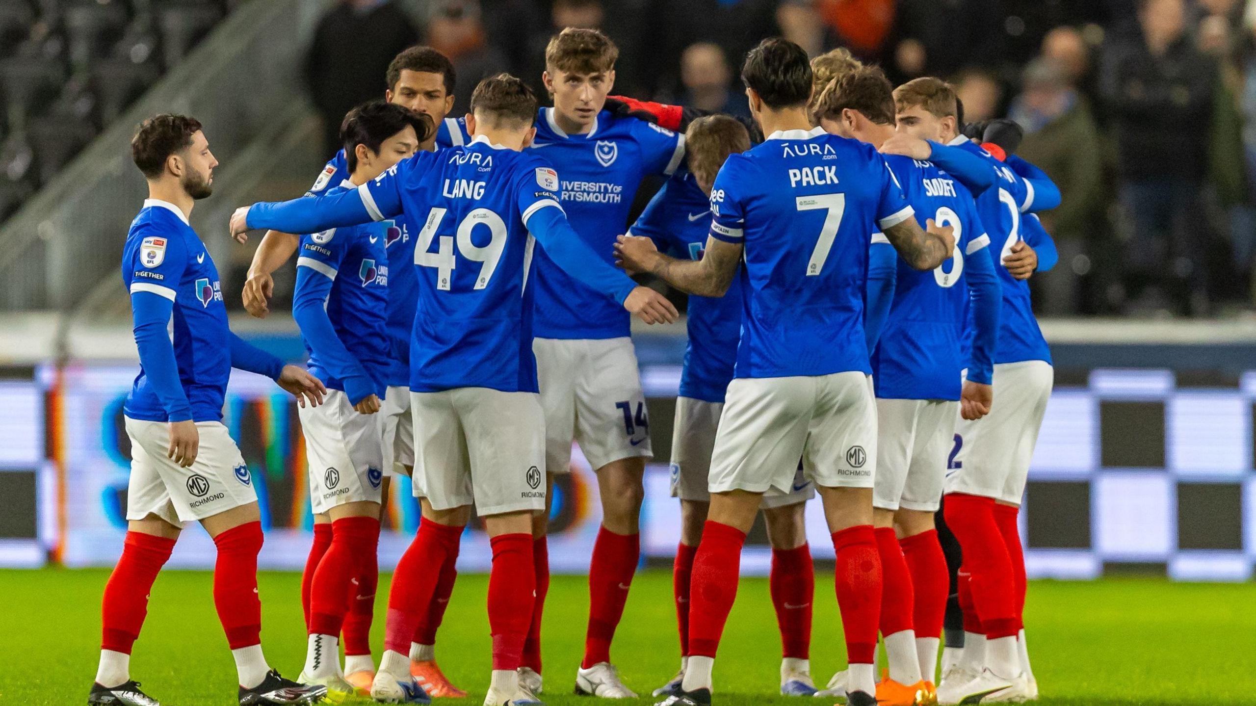 Portsmouth players huddling together during their match against Swansea