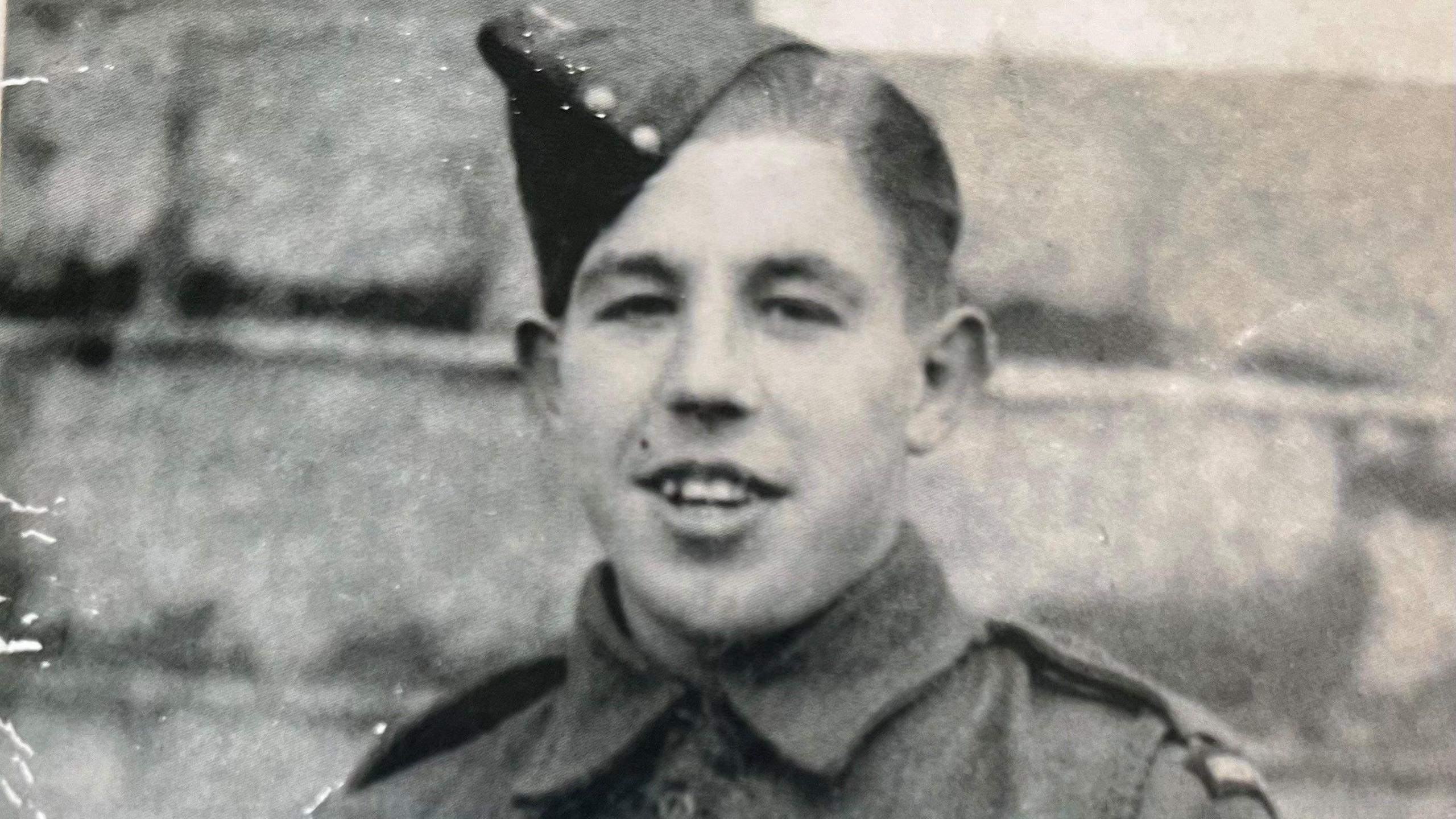 A young man wearing miliary uniform is show, the picture is black and white.