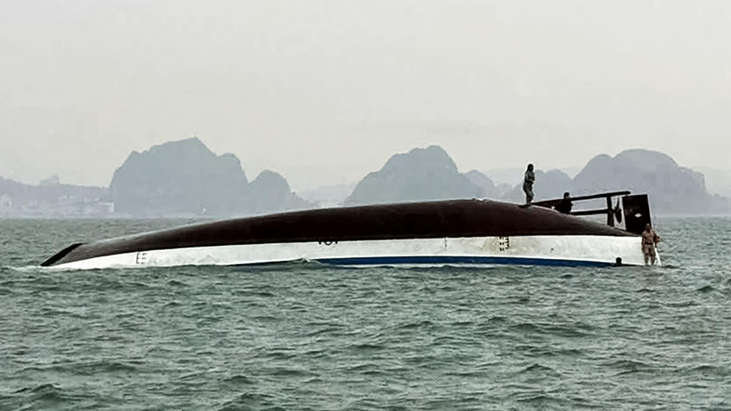 A man stands on a tourist boat that capsized in Ha Long Bay