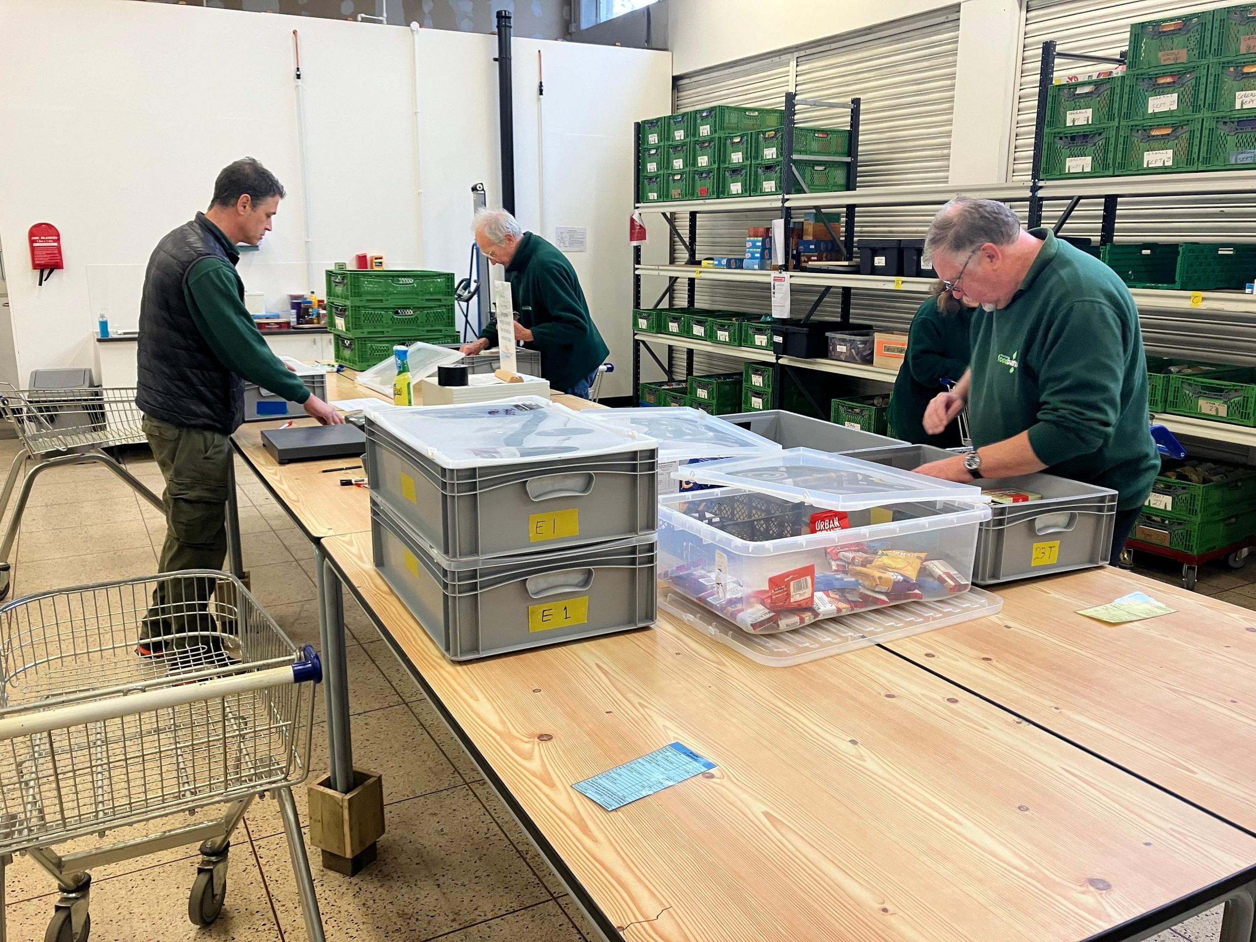 A picture of three men packing food into crates in a warehouse in Dunstable. They are wearing green tops.