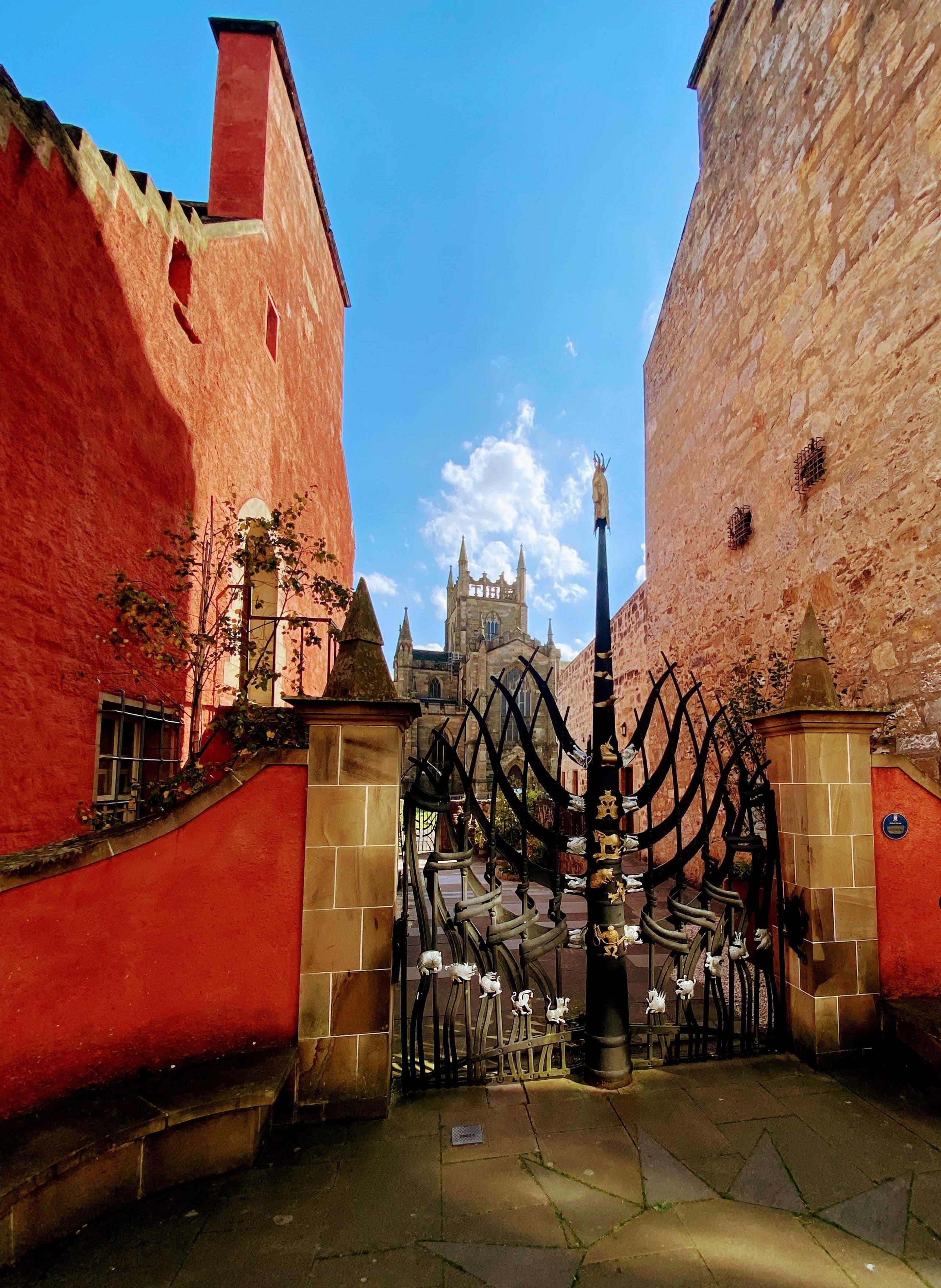 A beautiful ornate black iron gate leads to the cemetery surrounding Dunfermline Abbey - the red walls on either side adding to the drama.