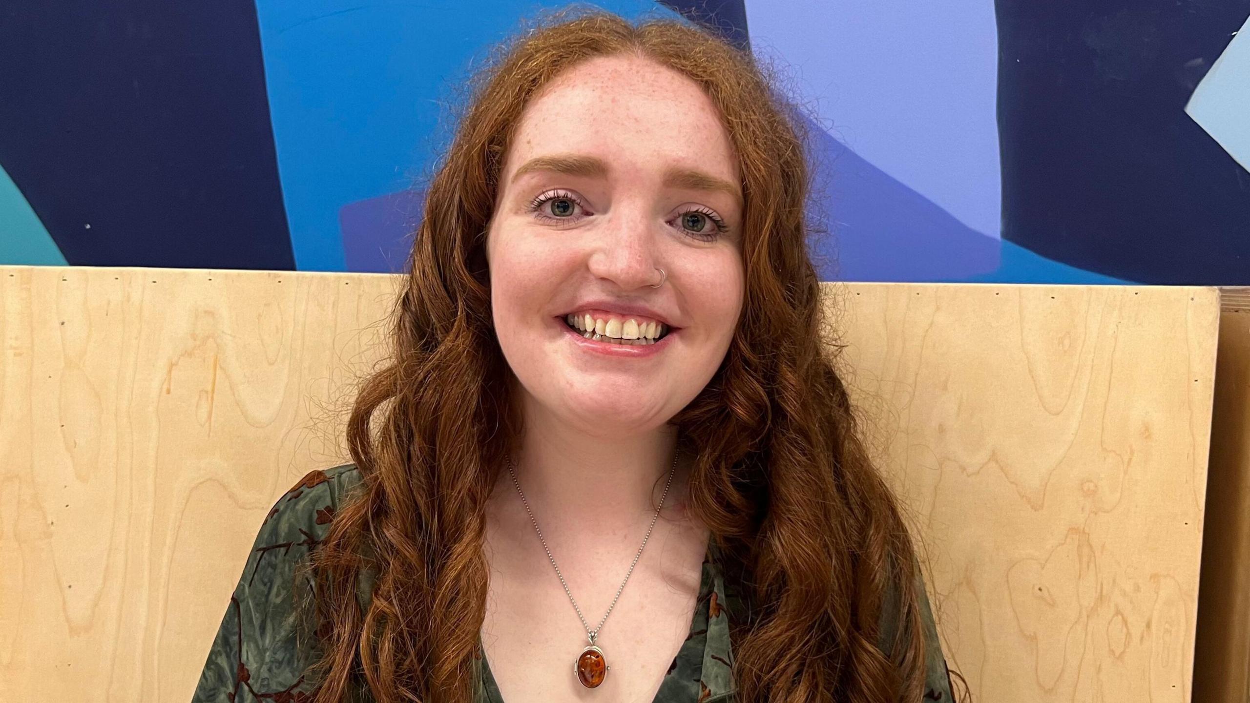 Girl with red hair and green dress on smiling for camera. 