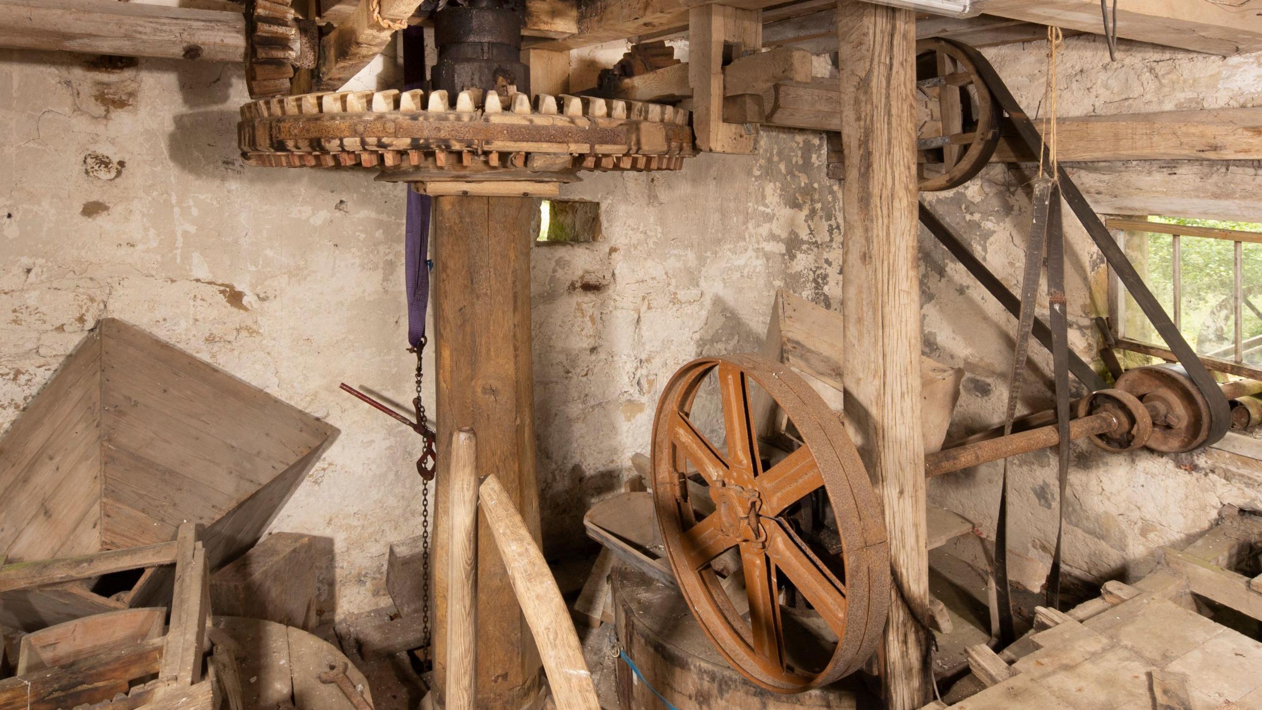 The interior of a traditional mill, likely the machinery room of an old watermill.