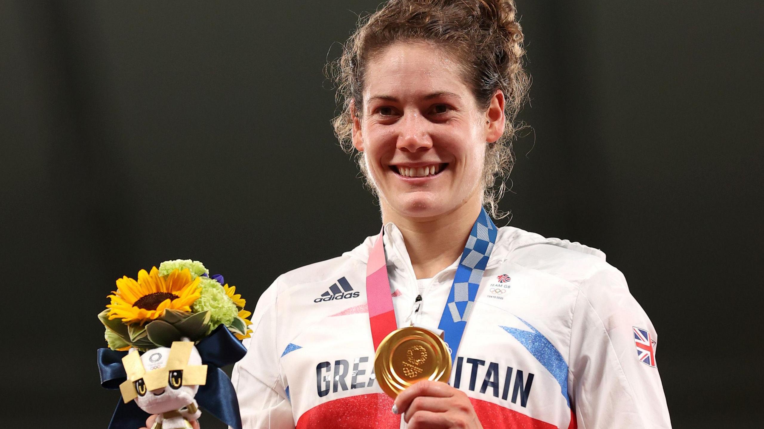 Kate French shows off her Olympic gold medal on the podium at Tokyo 2020