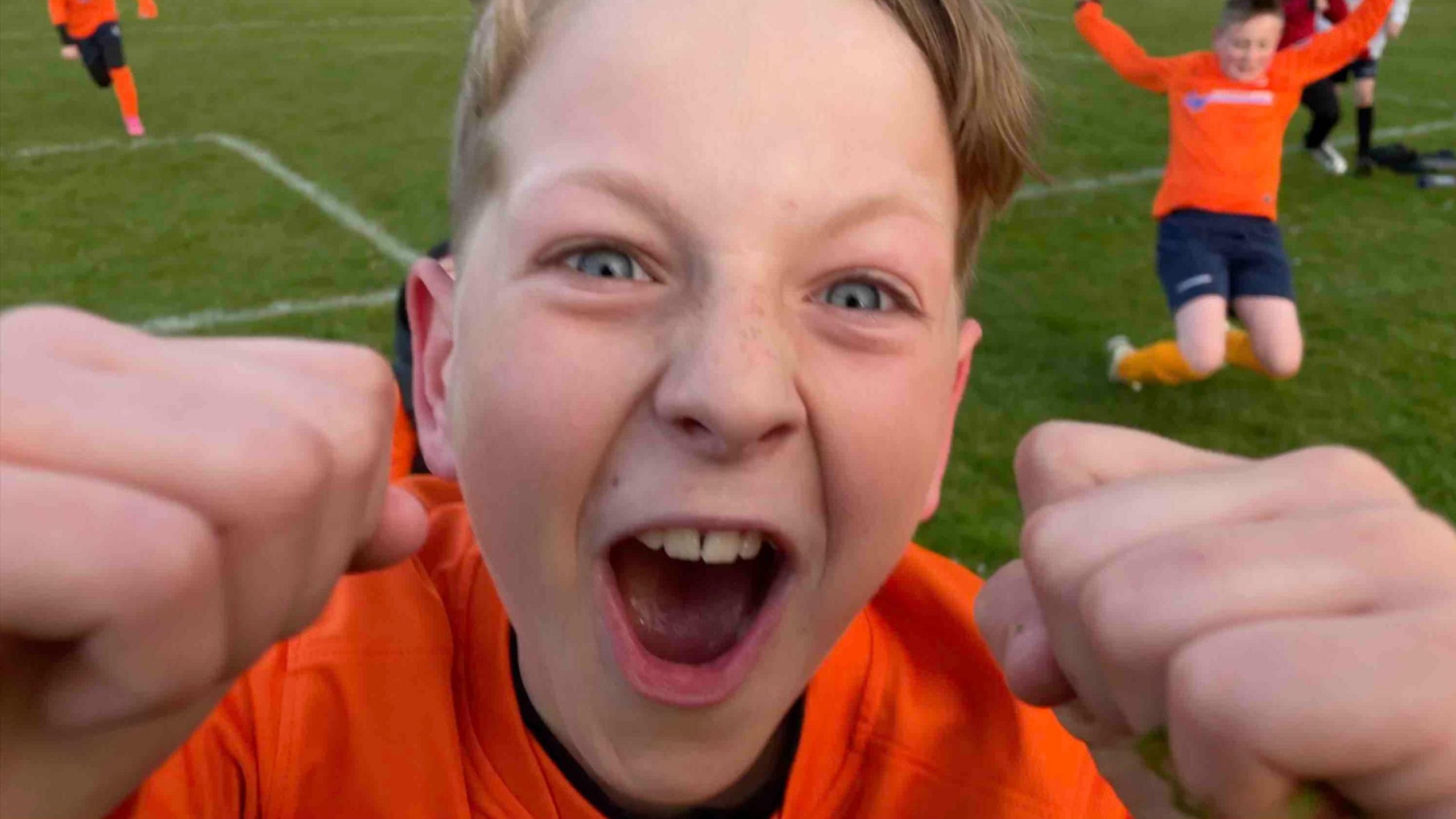 A boy shouting and clenching his fists, up close to the camera lens