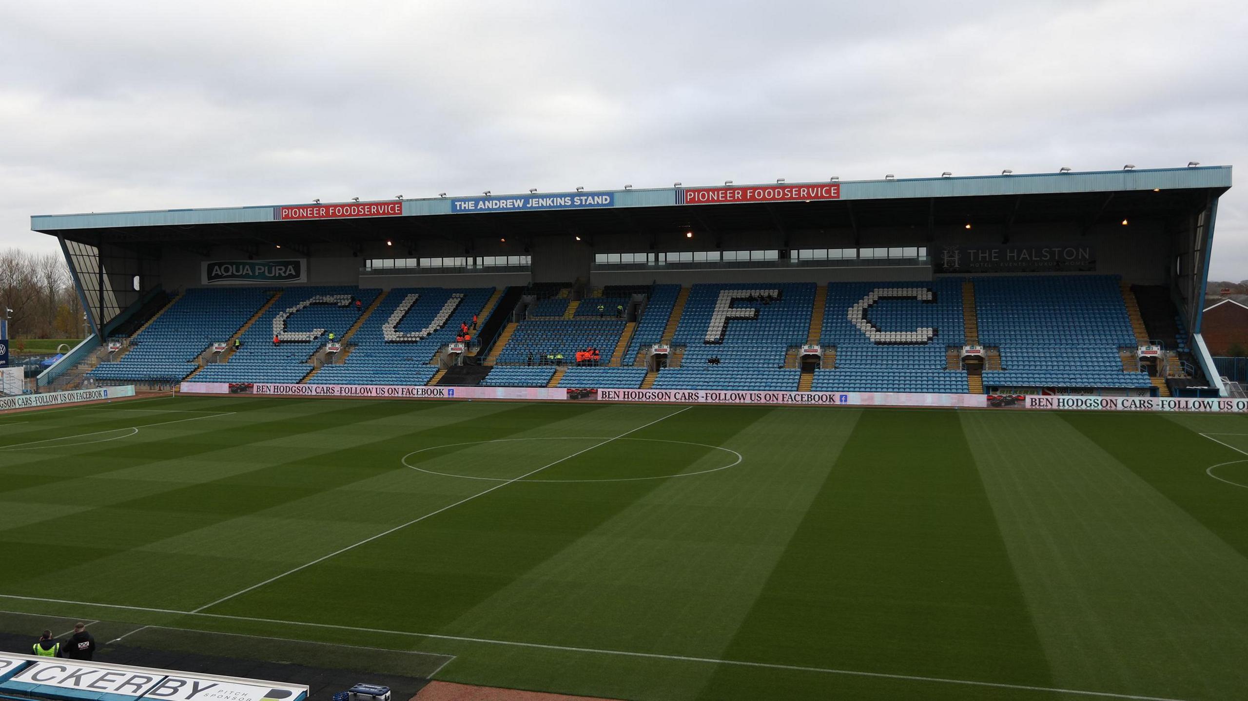 A view of Carlisle's Brunton Park East Stand with 'CUFC' written on the blue seats