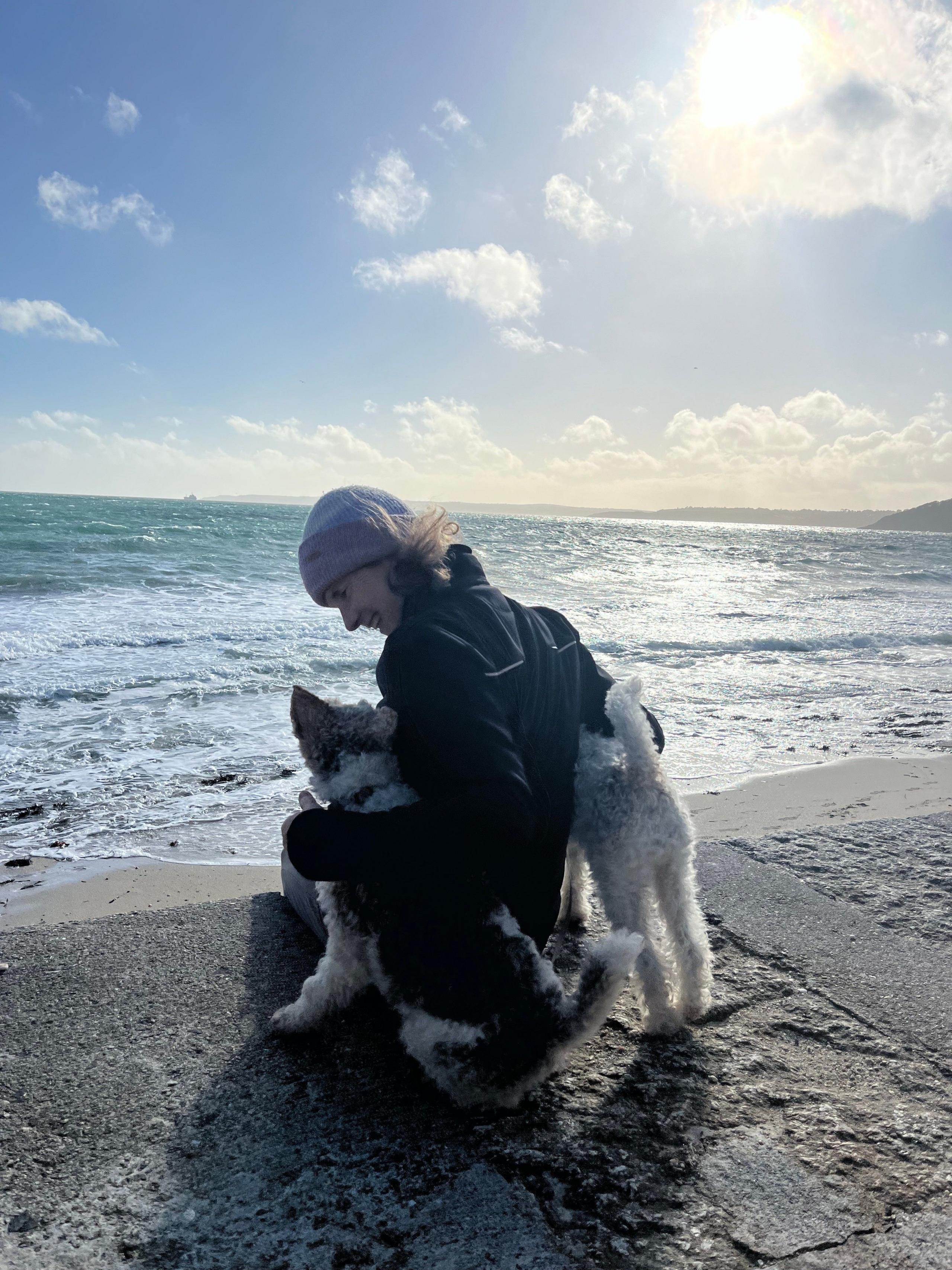 A woman and her dogs beside the sea