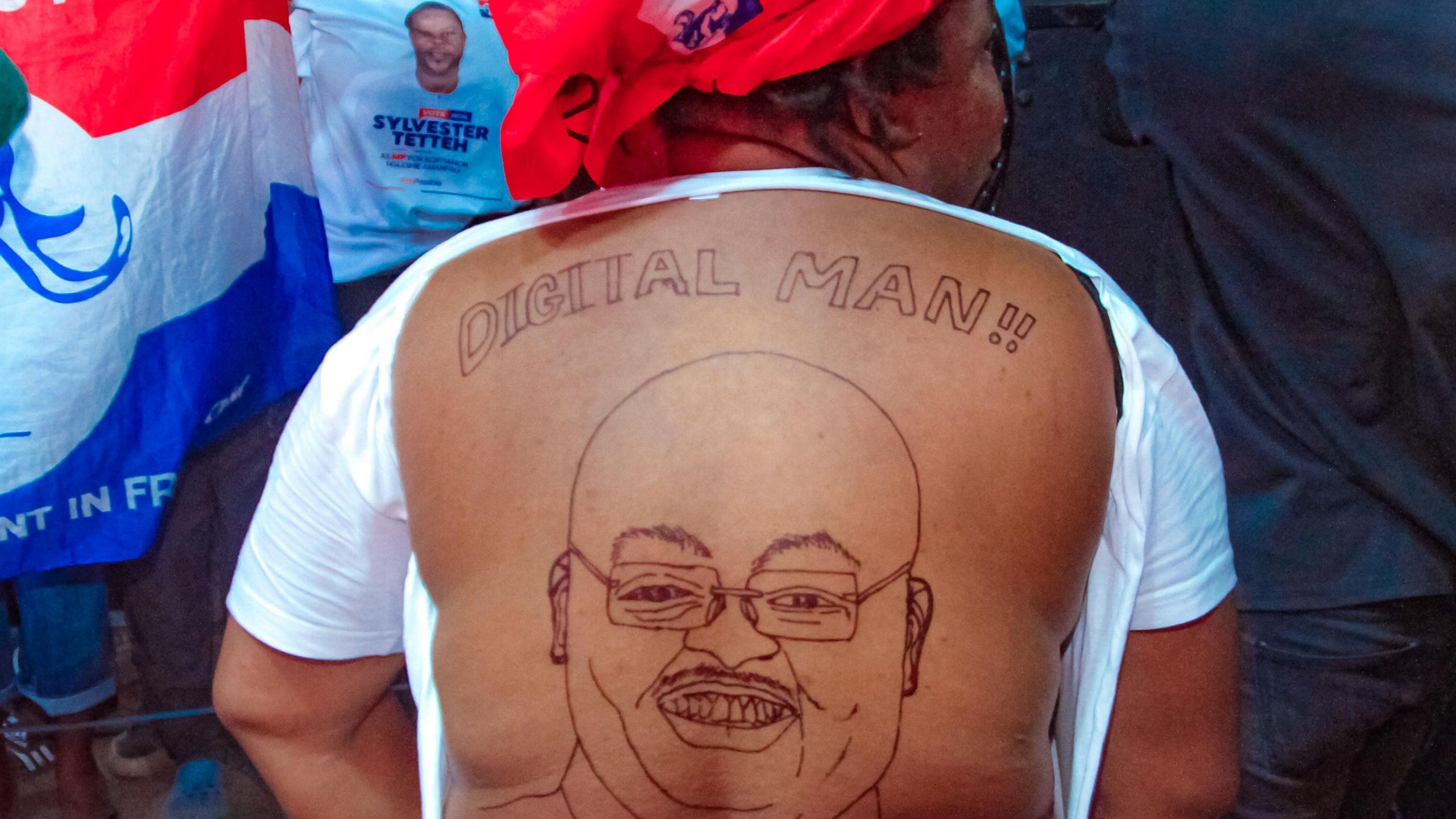 A supporter of Mahamudu Bawumia reveals her bare back, which is covered in a sketch of the presidential candidate. The words "digital man" are written above the drawing.