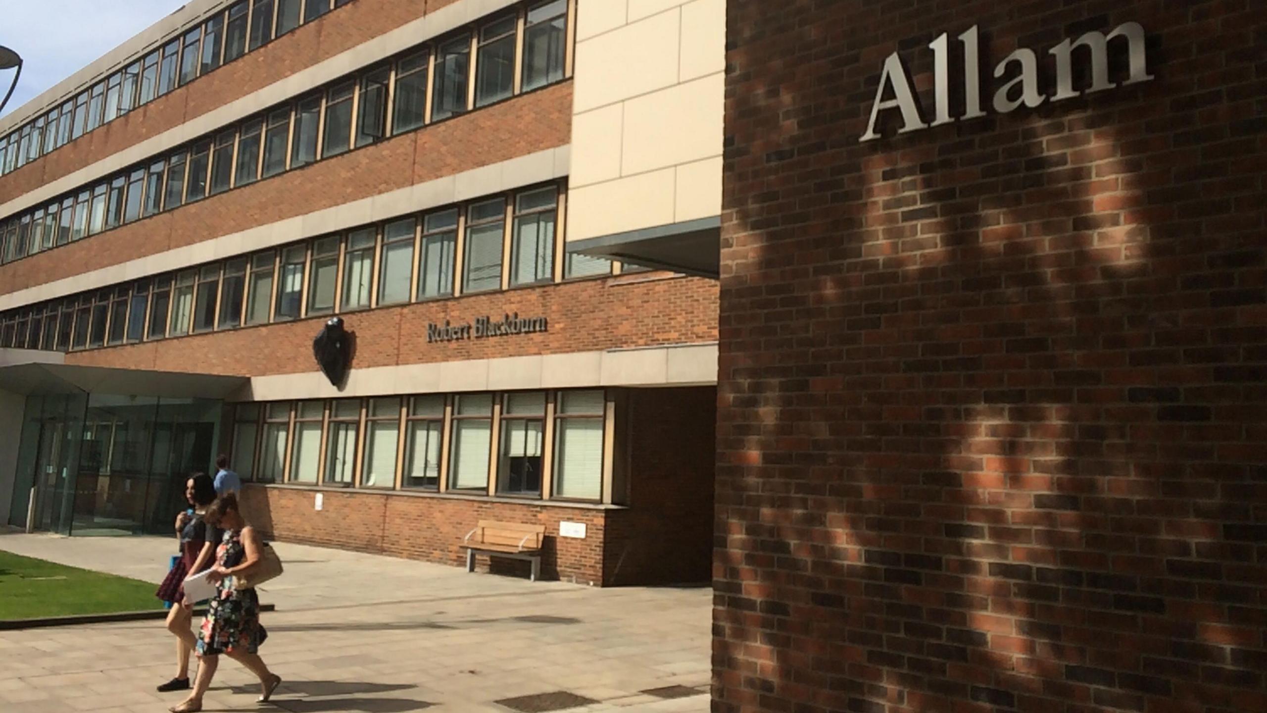 Students walking on campus in front of a building