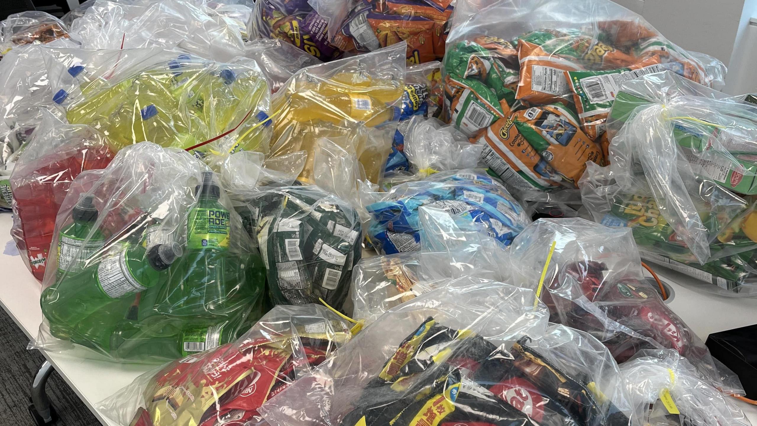 Clear plastics bags on a white table filled with seized goods including KitKat chocolate bars and Cheetos crisps