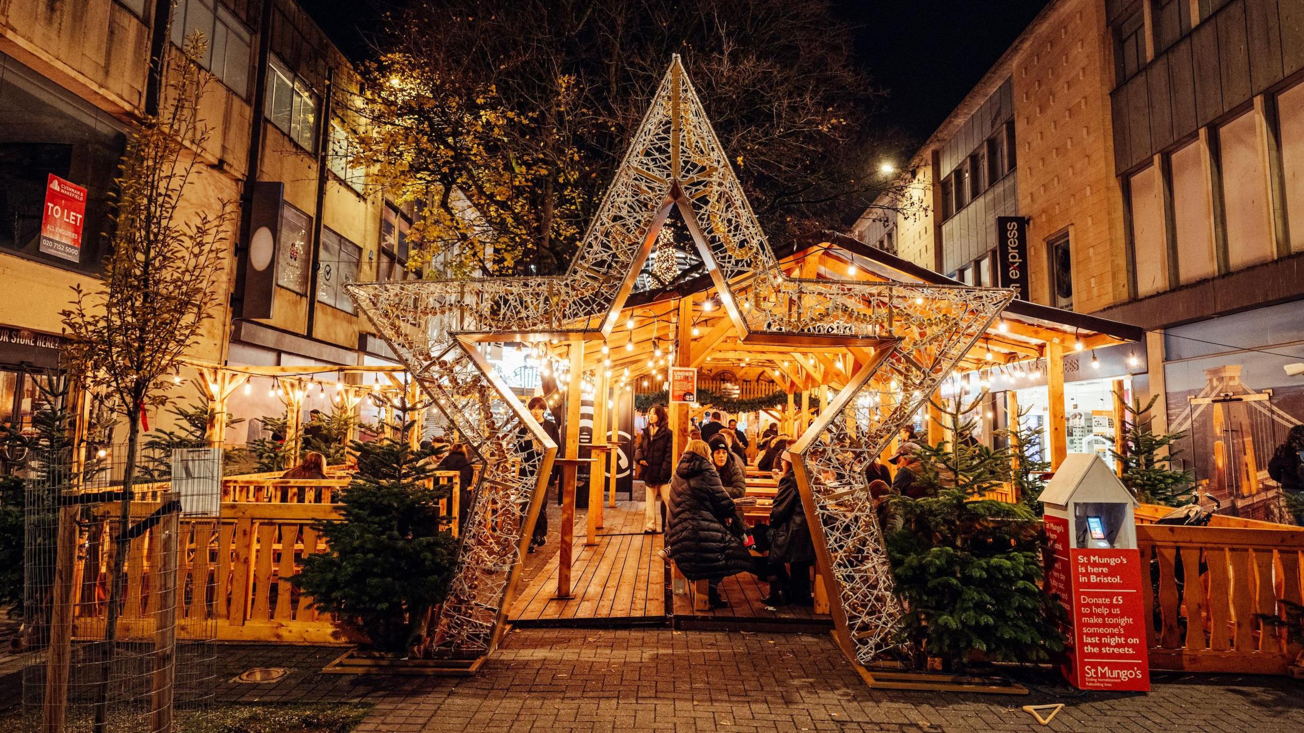 A Christmas market in Bristol, with a huge star-shaped arch in front of outdoor seating in a wooden decking area.