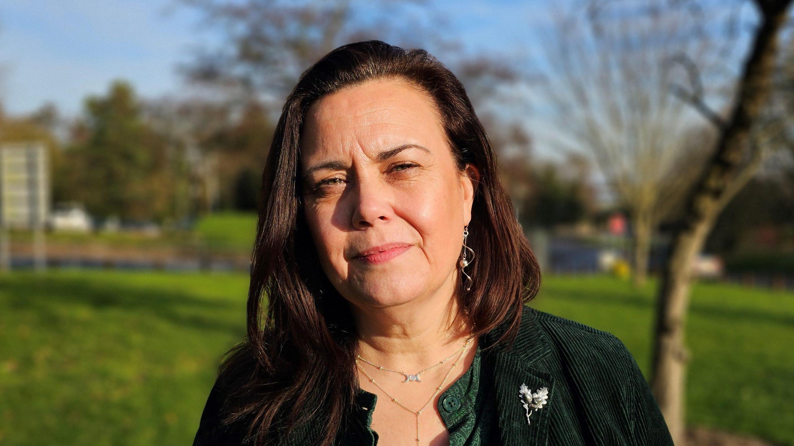 Jane James is looking at the camera and wearing a green top.