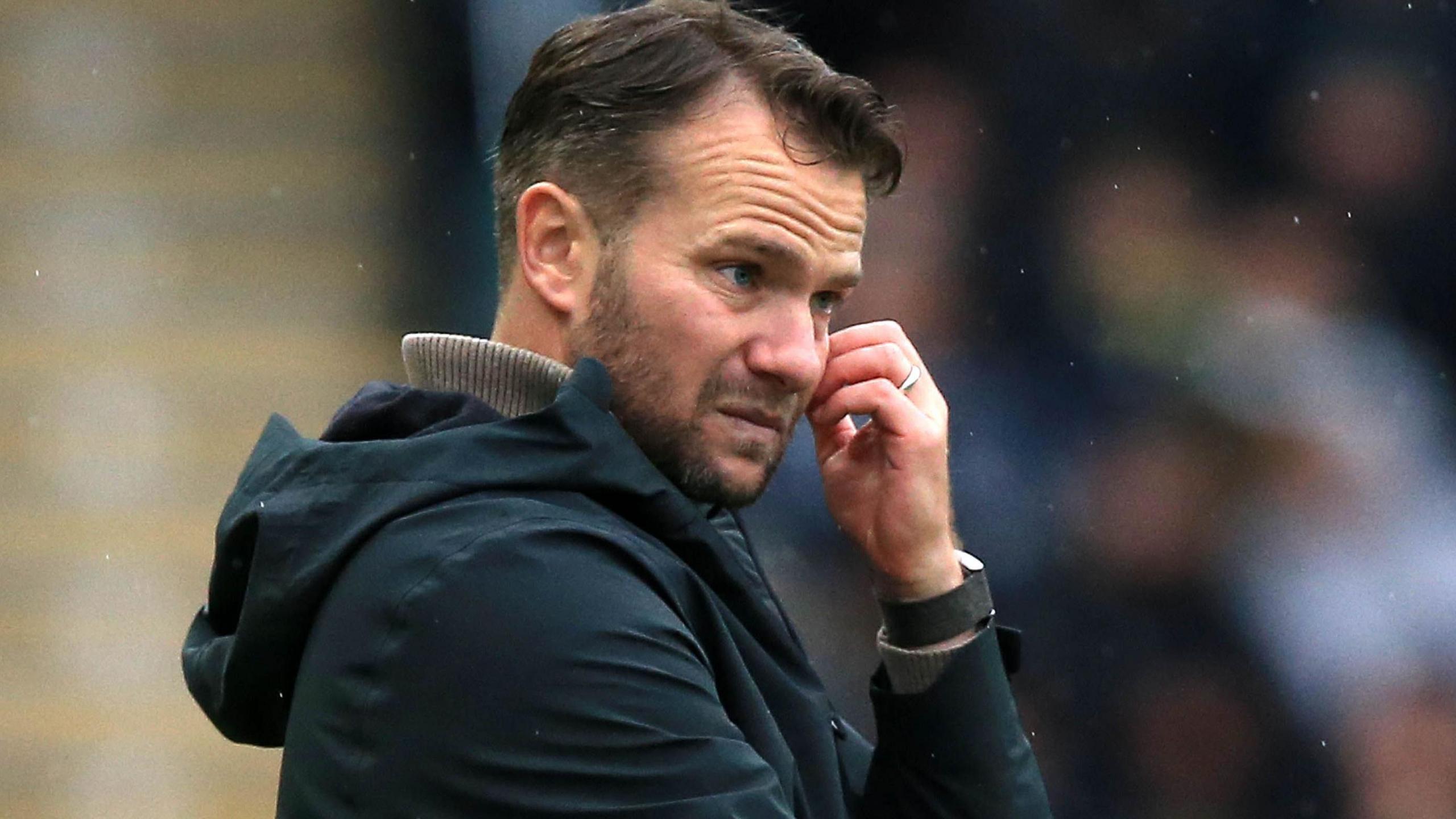 Tom Cleverley scratches his face while standing on the touchline