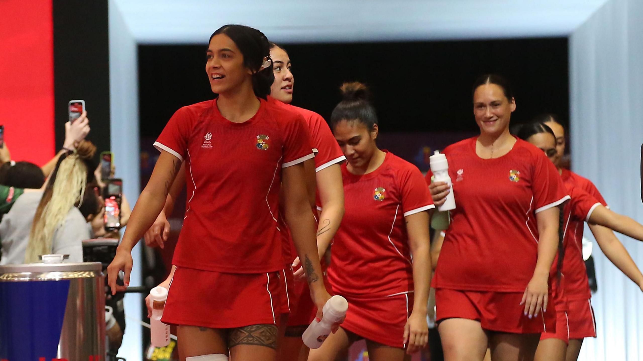 Hulita Veve leads out Tonga to face South Africa at the 2023 Netball World Cup, with players wearing red T-shirts and skirts