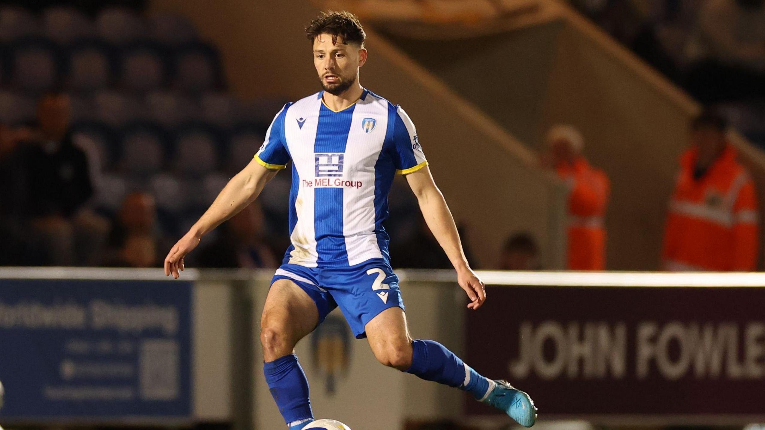 A photo of Rob Hunt, wearing his white and blue striped kit, playing for Colchester United during their match against his former side Swindon Town in April