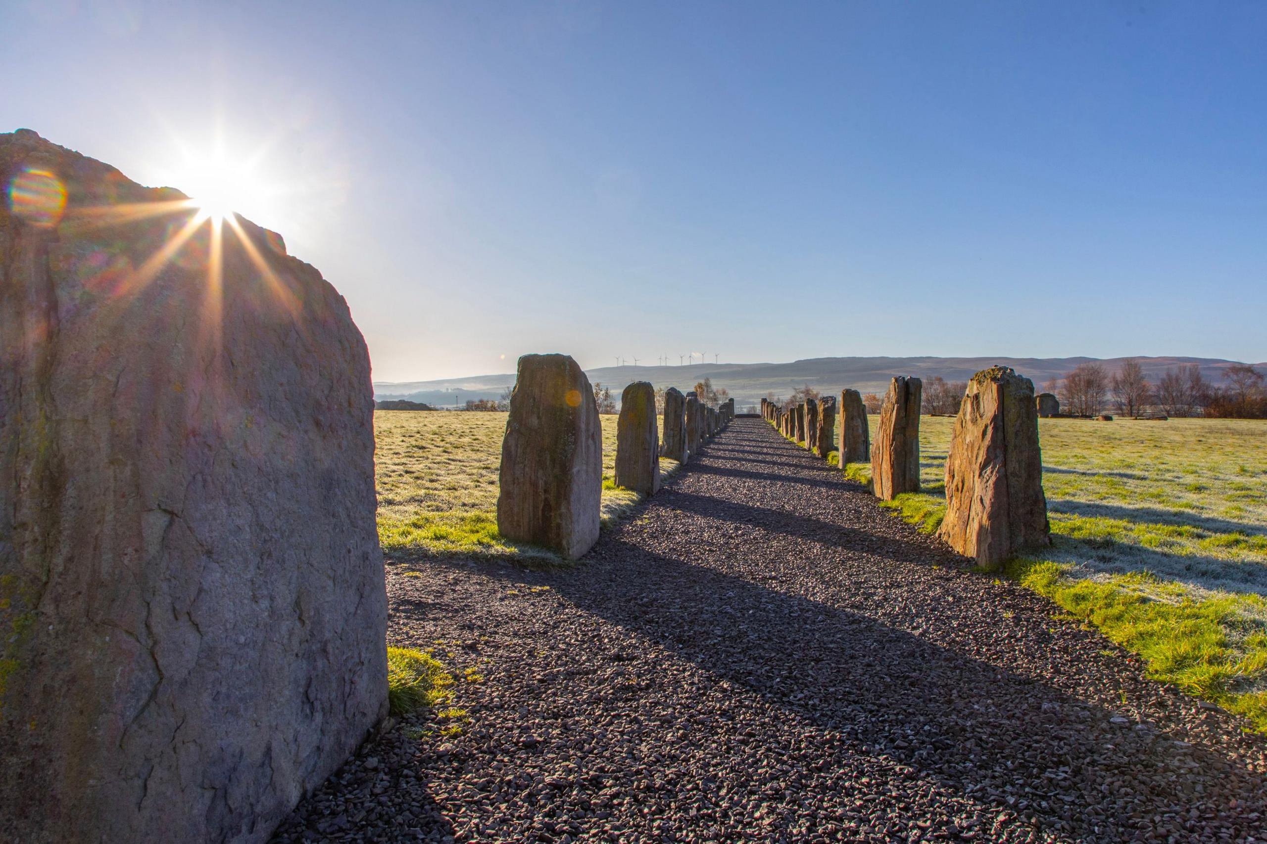 An alley way of stone chips through the countryside lined with large boulders on either side