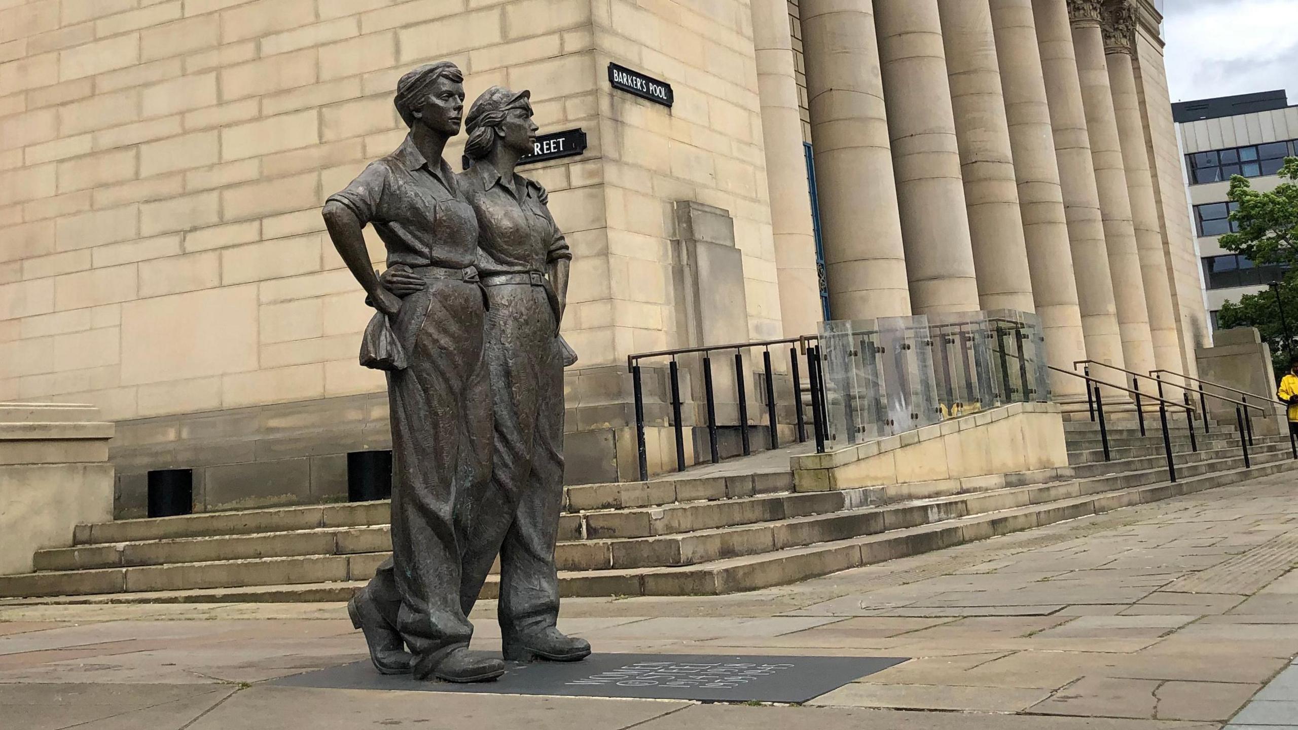 A statue of two women arm in arm wearing overalls.